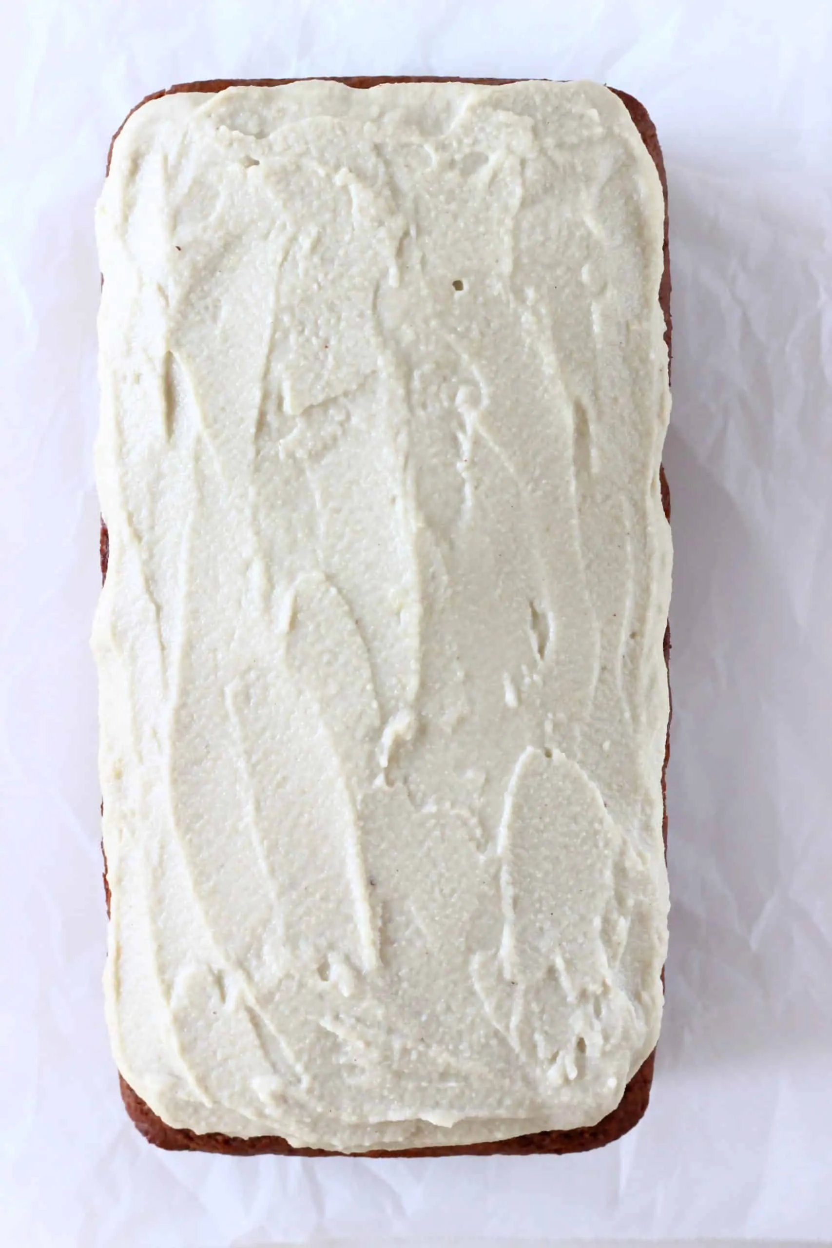 A gluten-free vegan gingerbread loaf cake with vegan cream cheese frosting spread on top