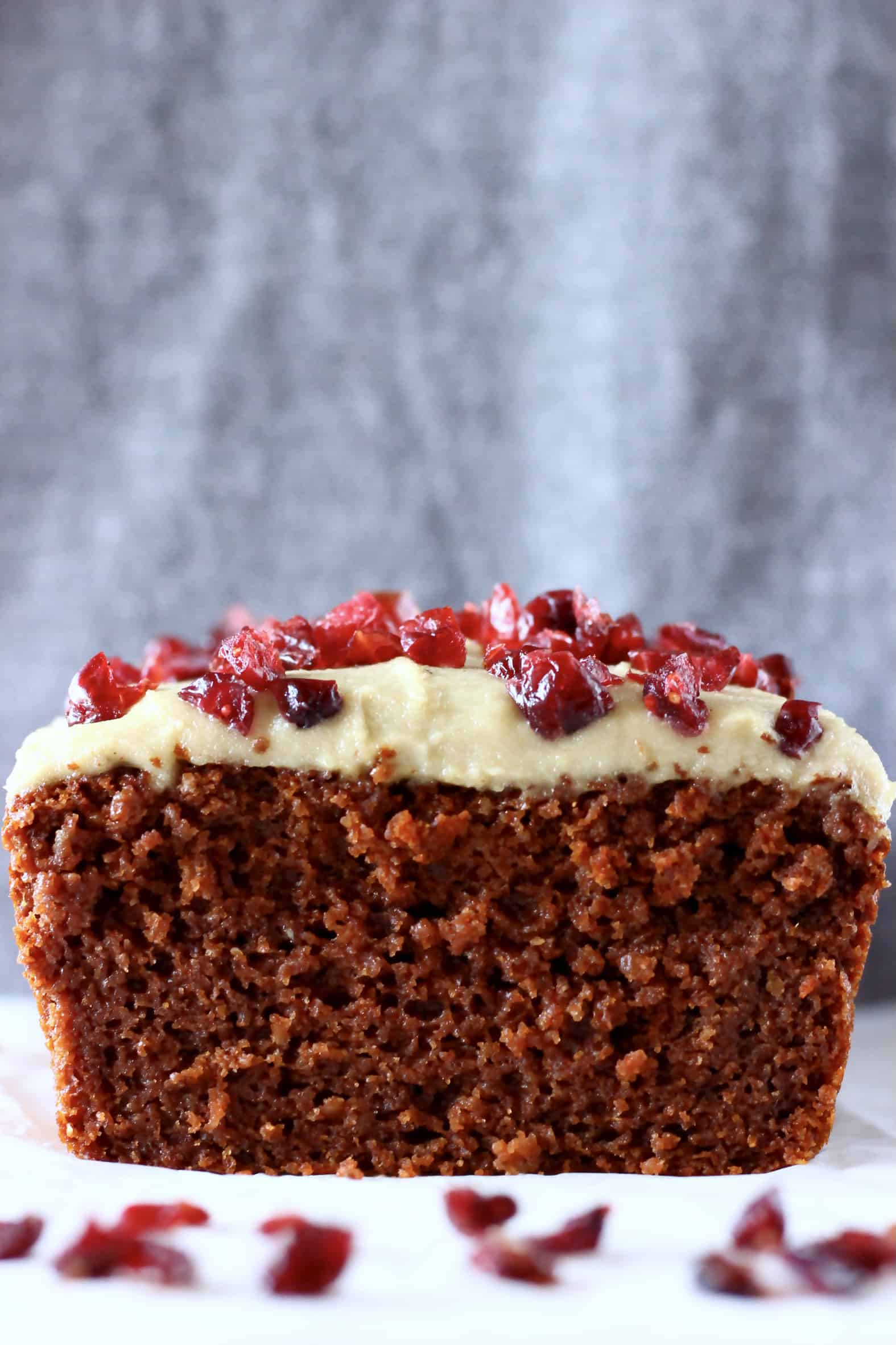 Sliced gingerbread loaf cake topped with white frosting and dried cranberries