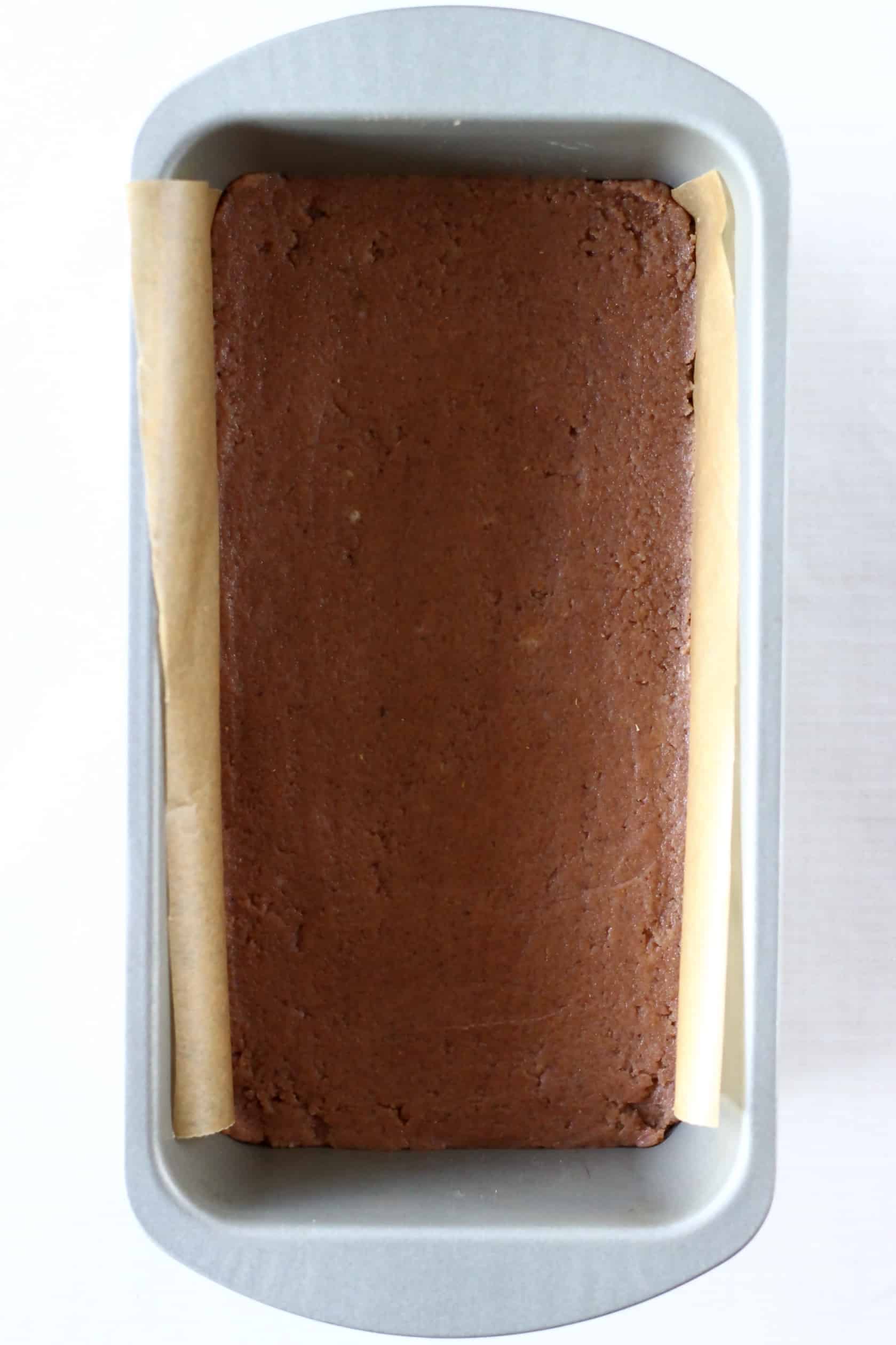 Raw gluten-free vegan gingerbread cookie bars dough in a loaf tin lined with baking paper