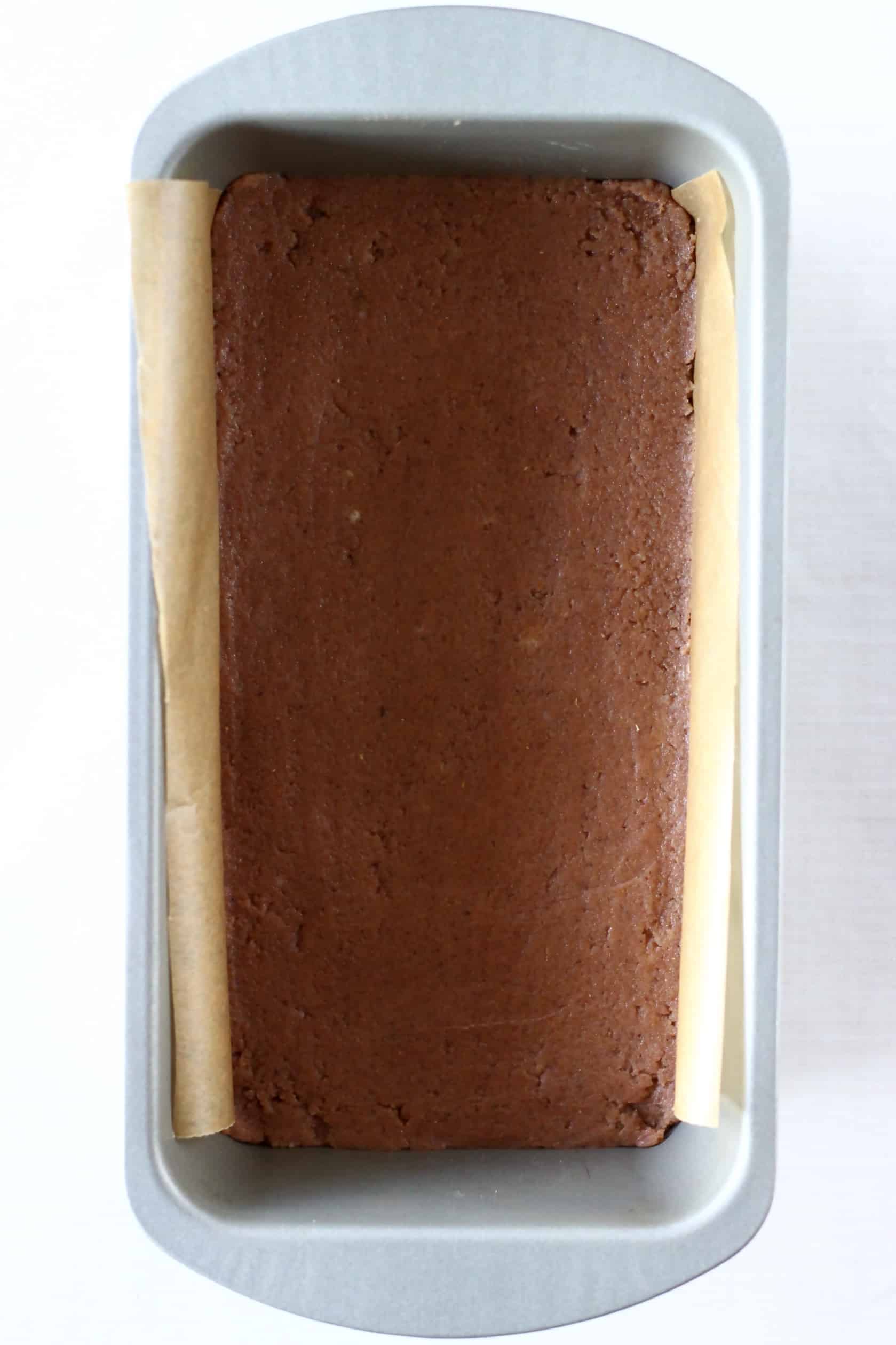Raw gluten-free vegan gingerbread cookie bars dough in a loaf tin lined with baking paper