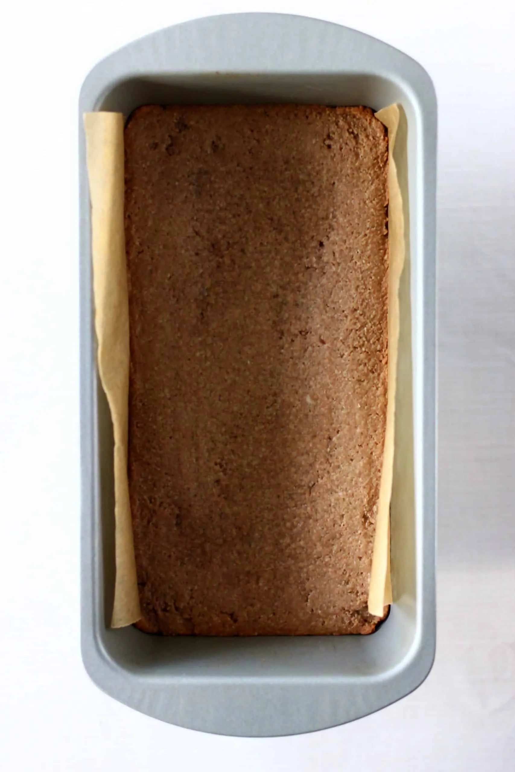 Baked gluten-free vegan gingerbread cookie bars in a loaf tin lined with baking paper