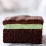 A vegan peppermint brownie with green peppermint cream and chocolate ganache