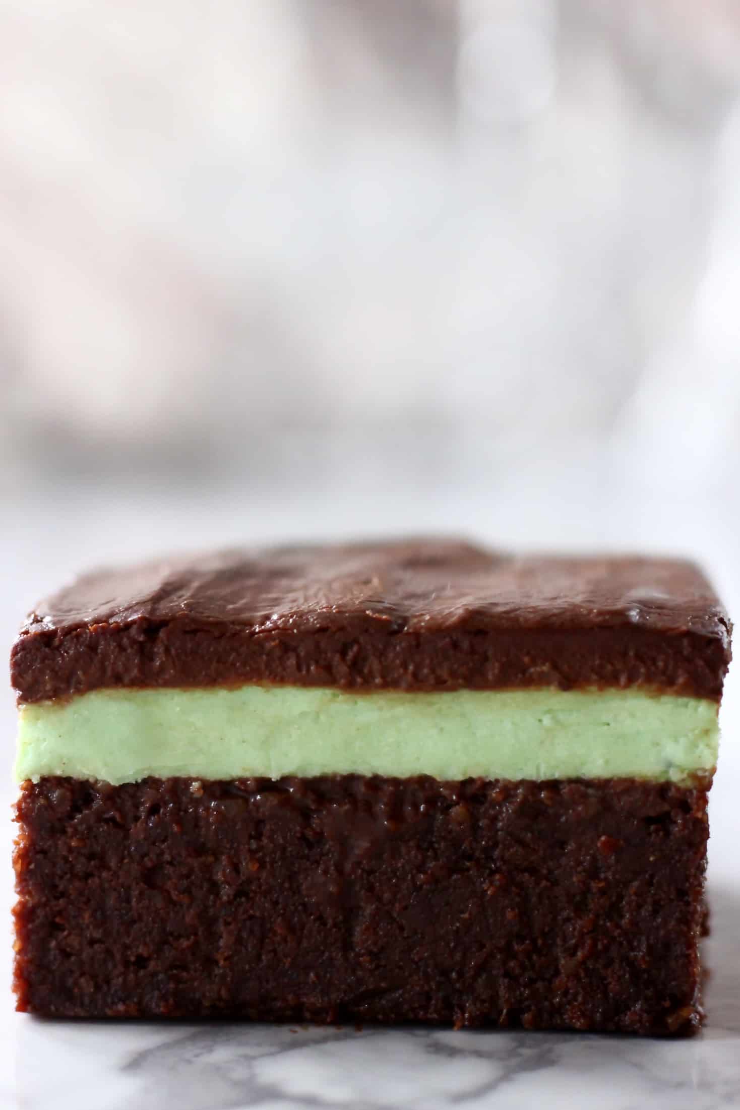 A vegan peppermint brownie with green peppermint cream and chocolate ganache