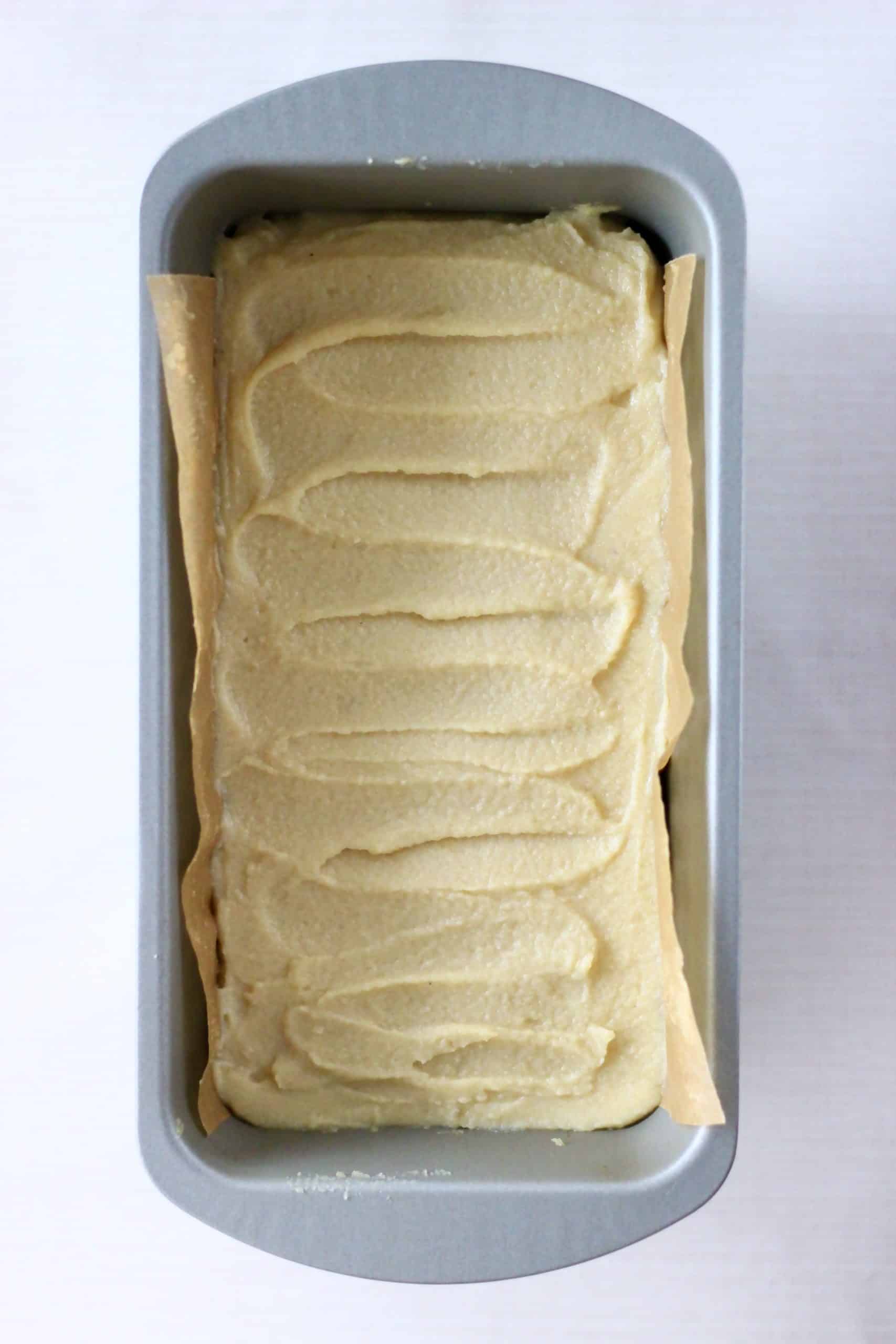 Vegan cream cheese frosting spread over gluten-free vegan gingerbread cookie bars in a loaf tin