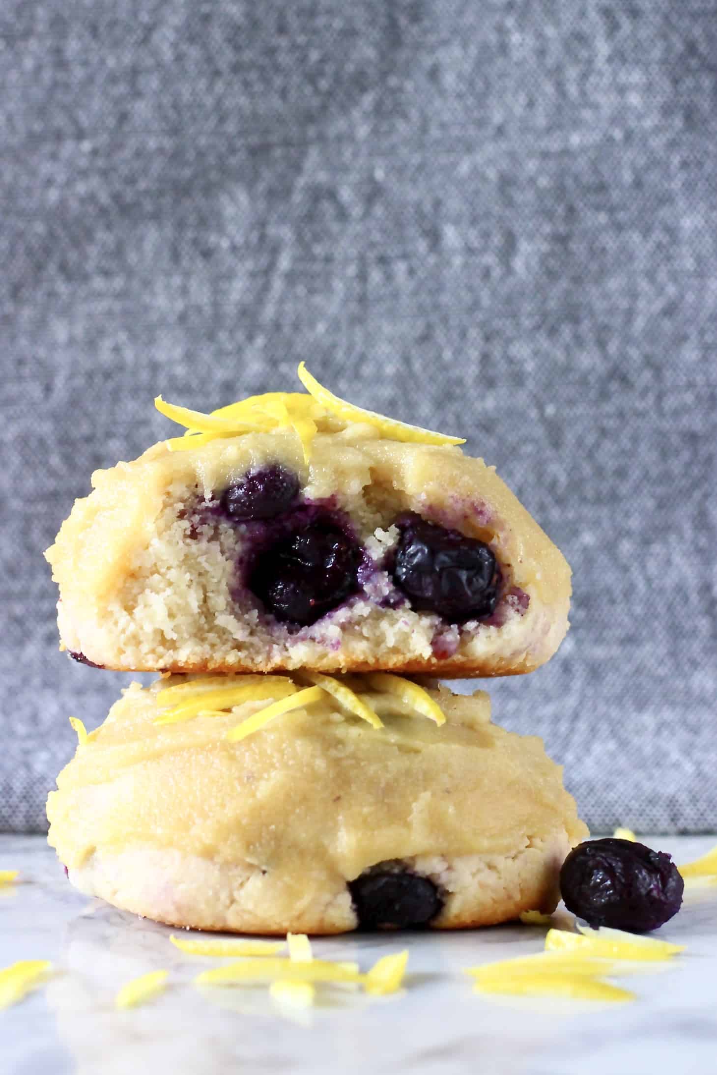 Two gluten-free vegan lemon blueberry cookies stacked on top of each other with a bite taken out of one