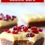 Three gingerbread cookie bars with frosting and dried cranberries with a bite taken out of one