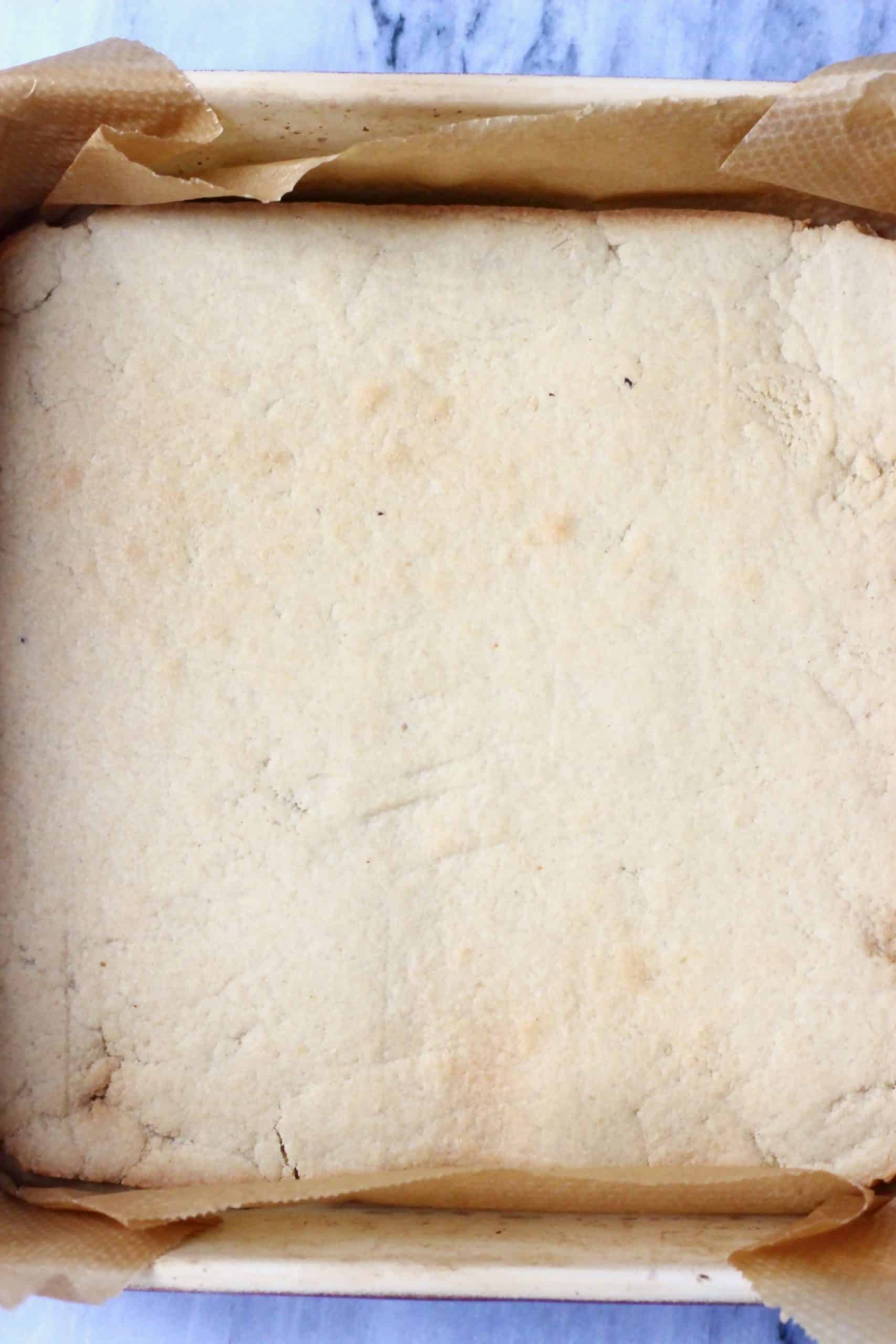 Baked gluten-free vegan crumble bar base in a square baking tin