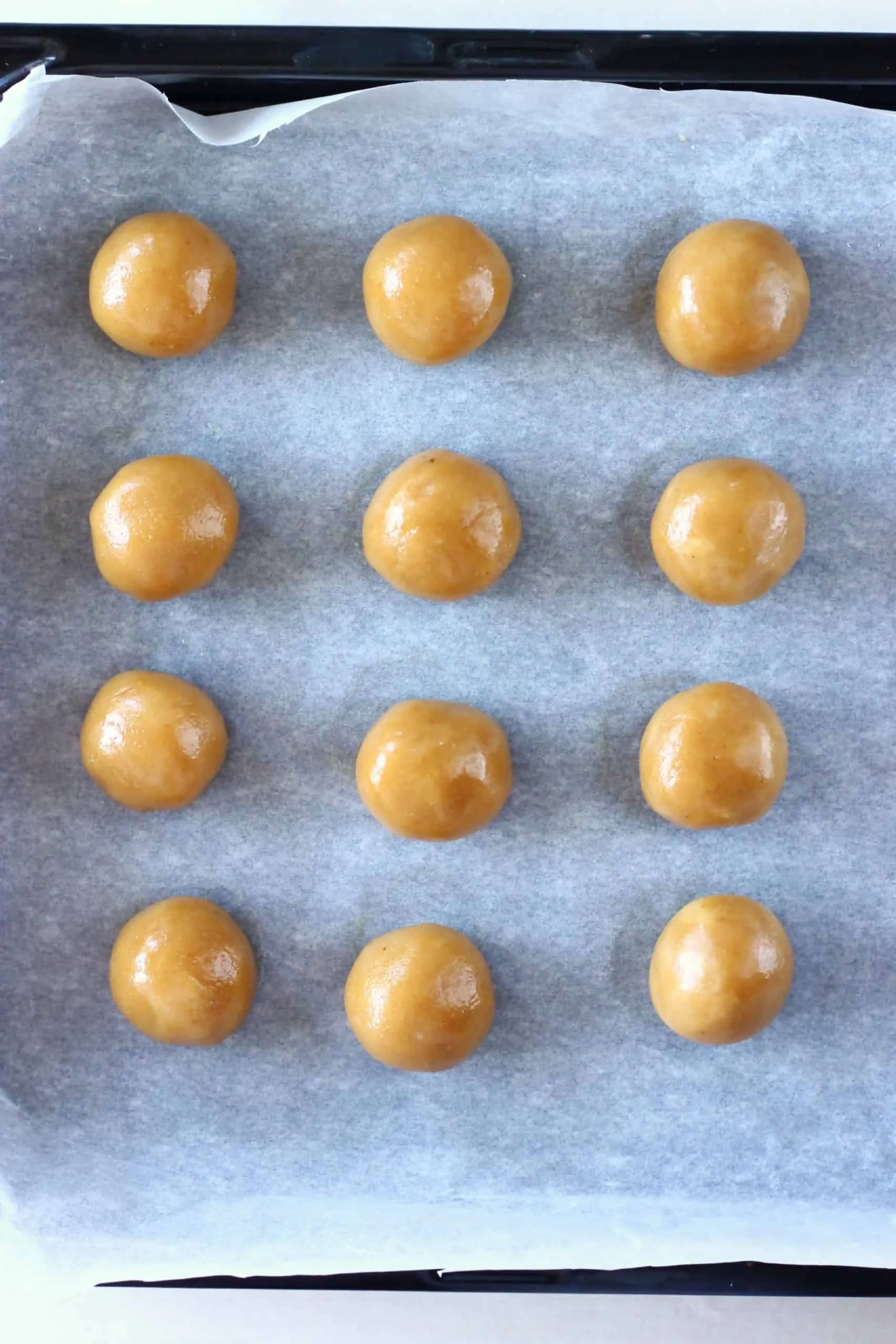 Twelve healthy peanut butter balls on a baking tray lined with baking paper