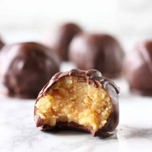 Chocolate-covered healthy peanut butter balls with a bite taken out of one