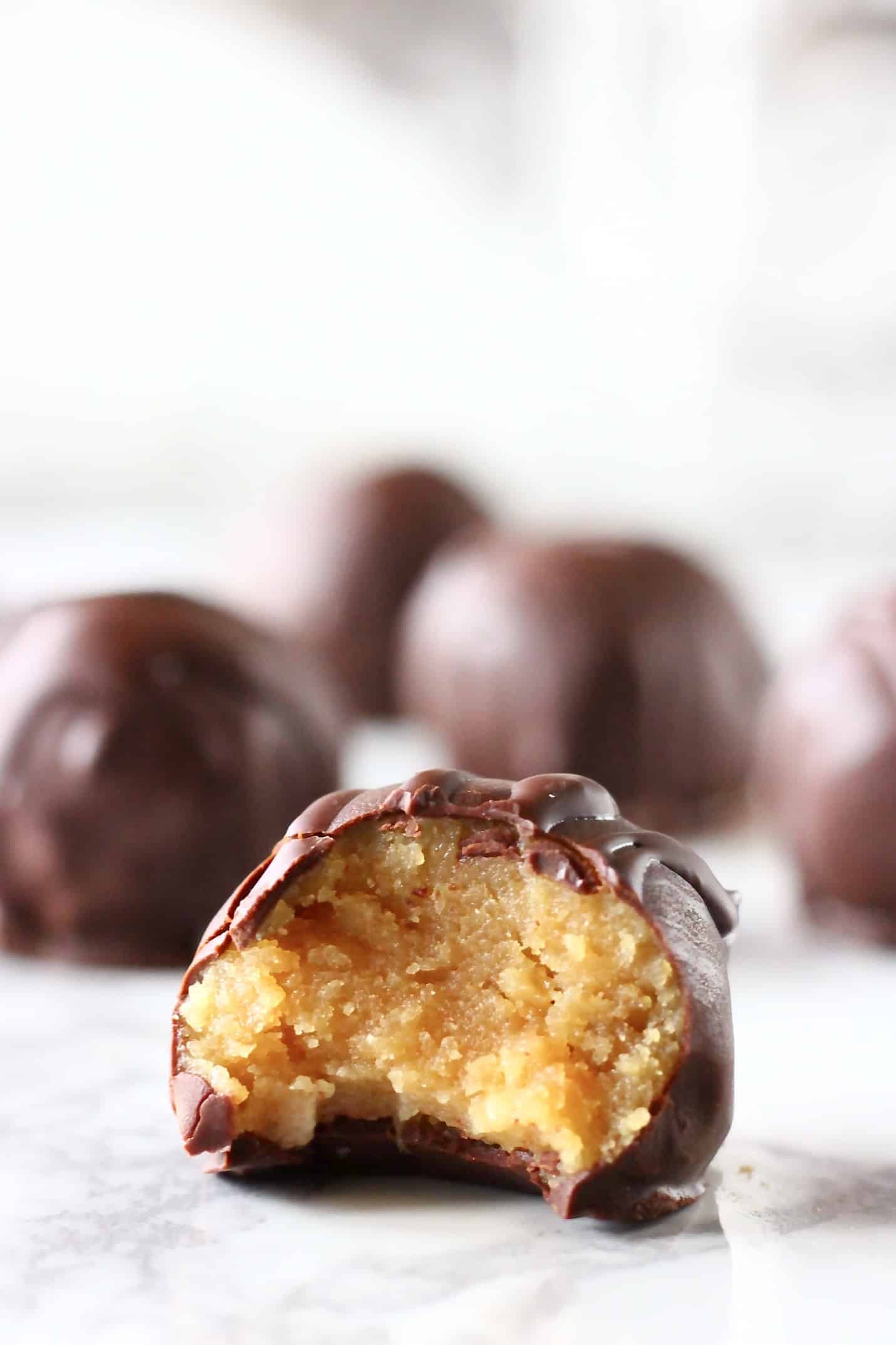 Chocolate-covered healthy peanut butter balls with a bite taken out of one