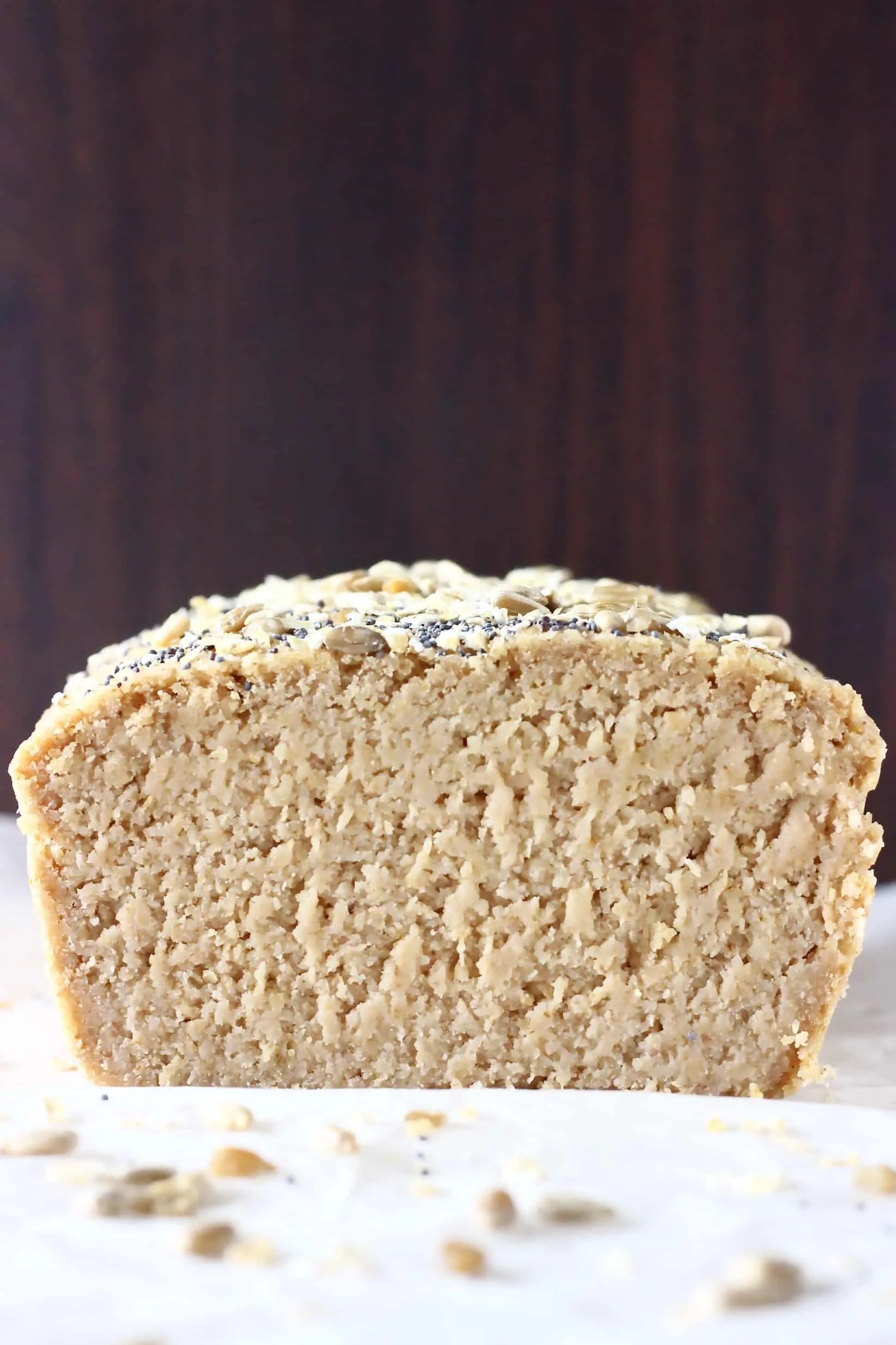 A sliced cross-section of a loaf of oat flour bread topped with oats and seeds