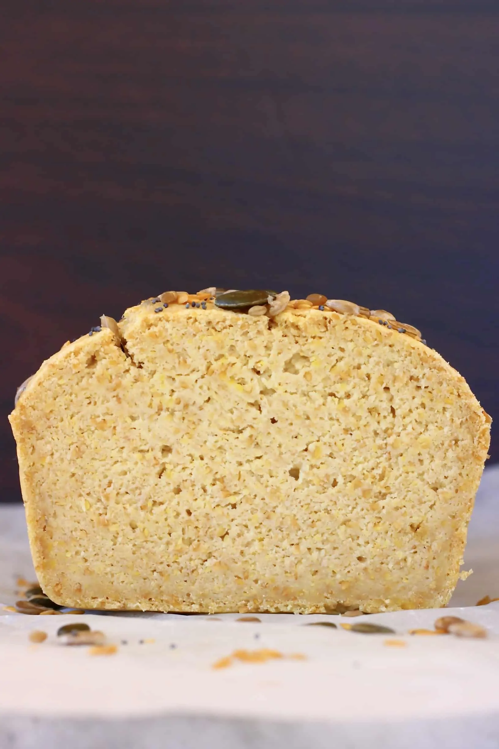 A sliced loaf of flaxseed bread against a dark brown background