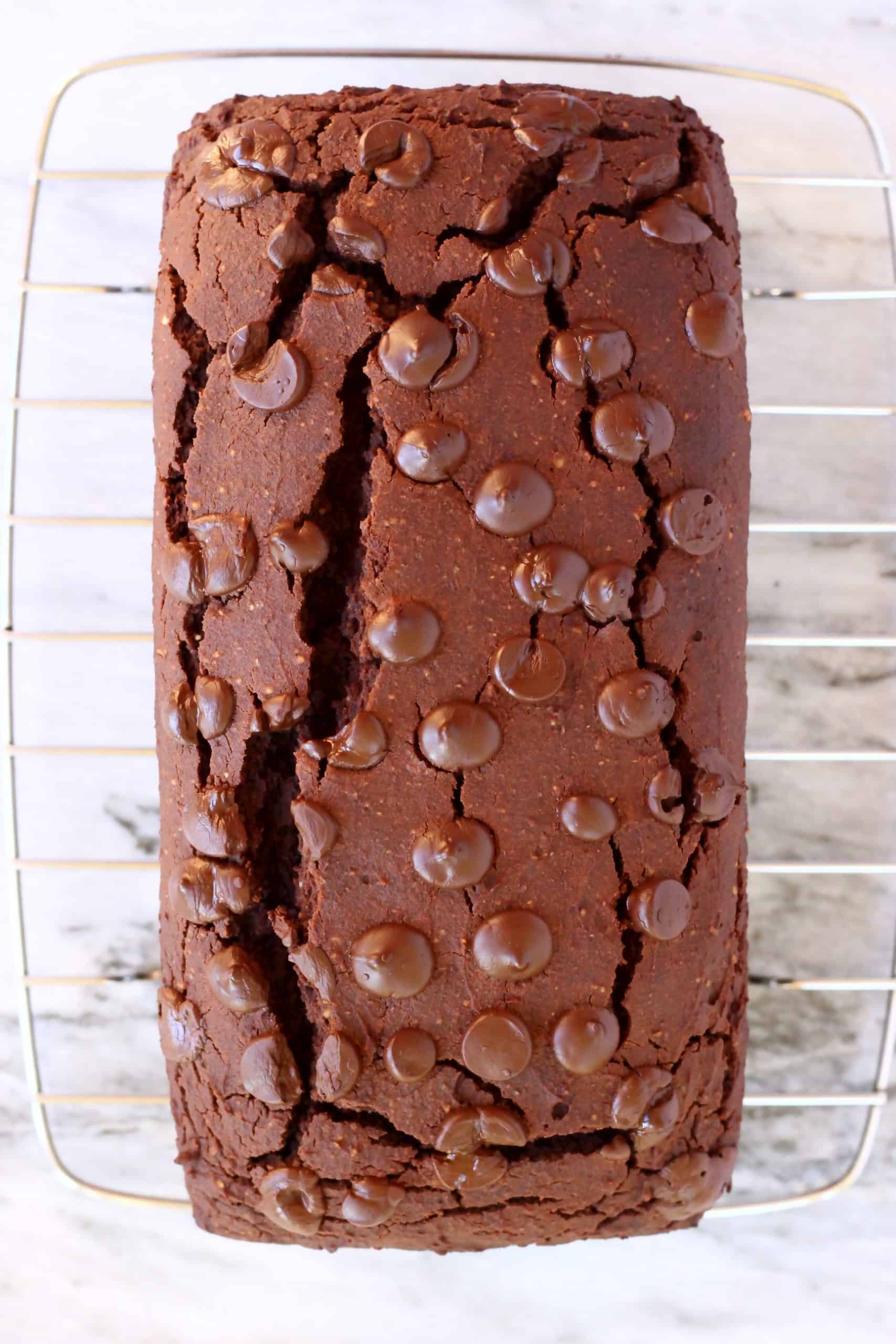 Sweet potato chocolate cake loaf topped with chocolate chips on a wire rack
