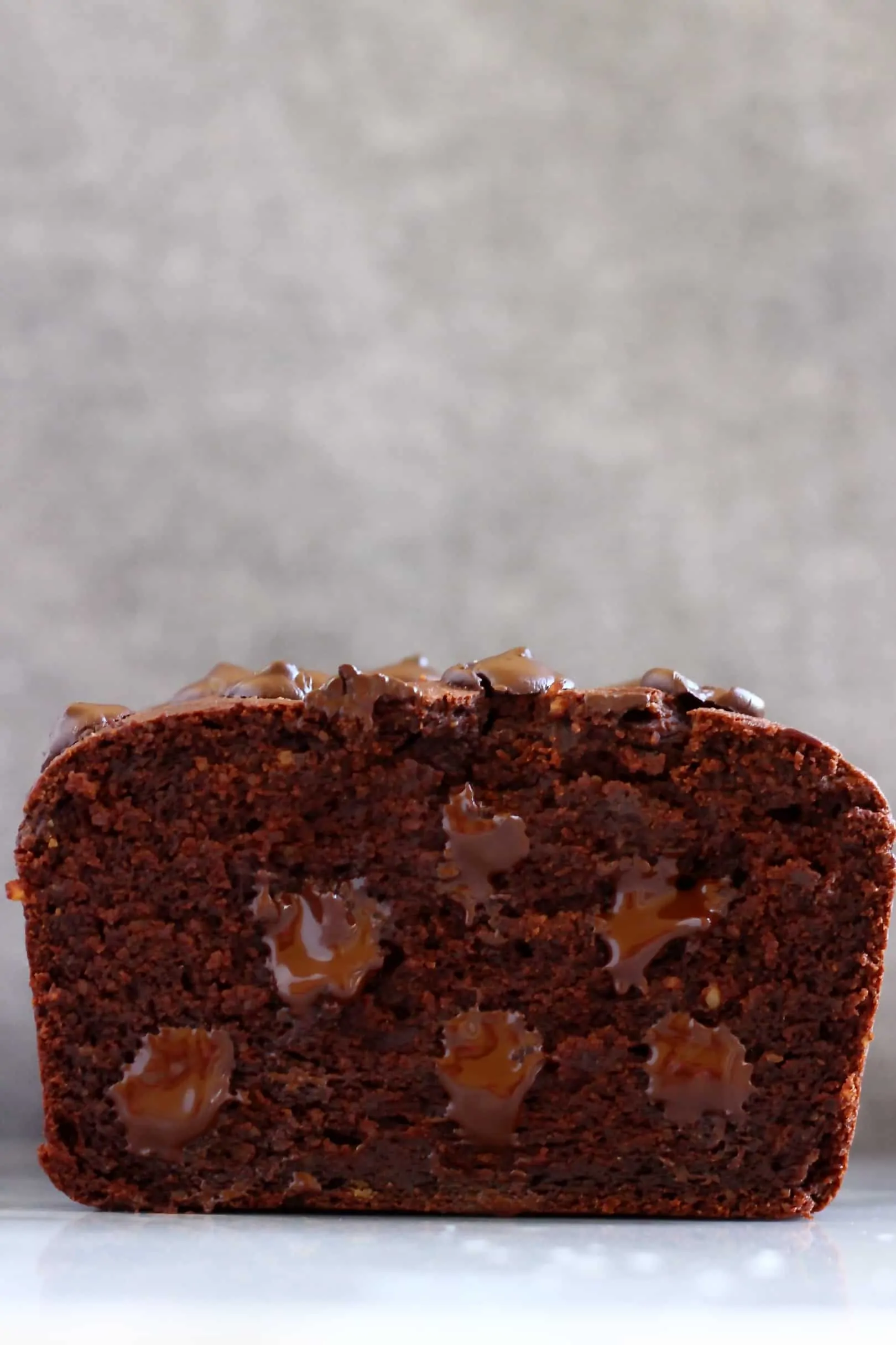 Sliced sweet potato chocolate loaf cake with chocolate chips against a grey background