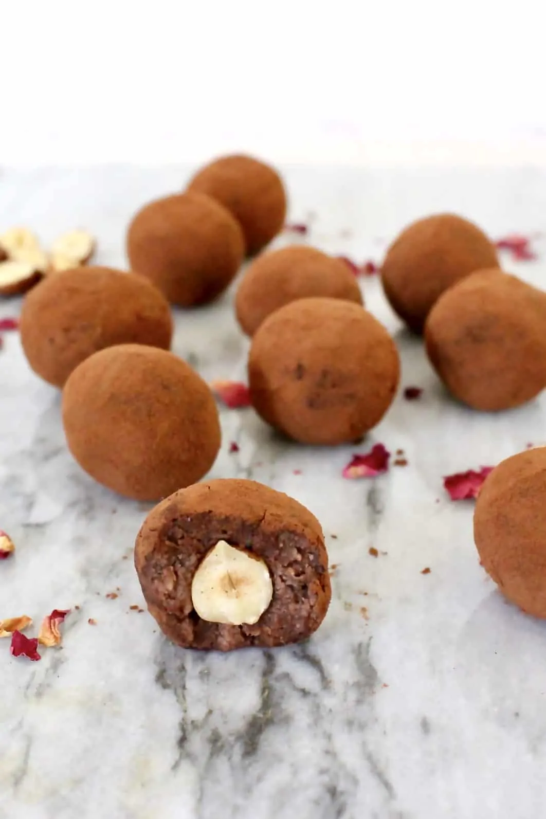 Ten chocolate hazelnut truffles with a mouthful taken out of one