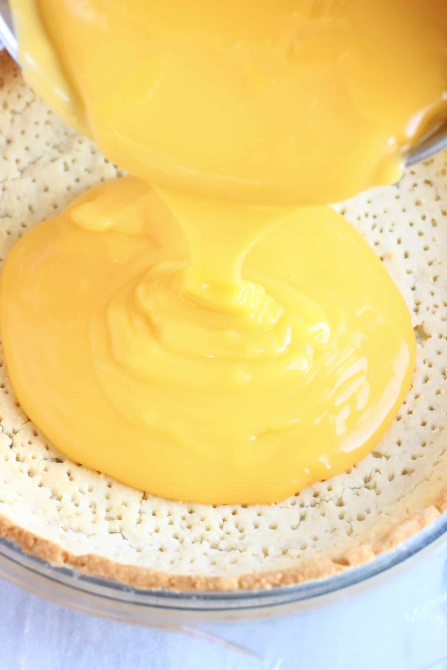 Vegan lemon custard being poured into a gluten-free vegan tart crust