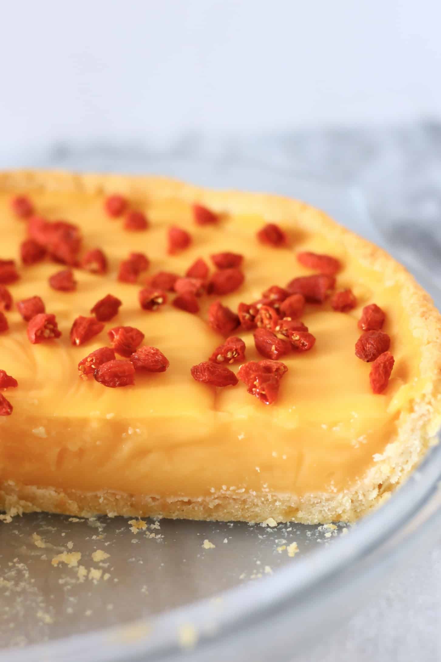 Gluten-free vegan lemon tart topped with goji berries in a pie dish