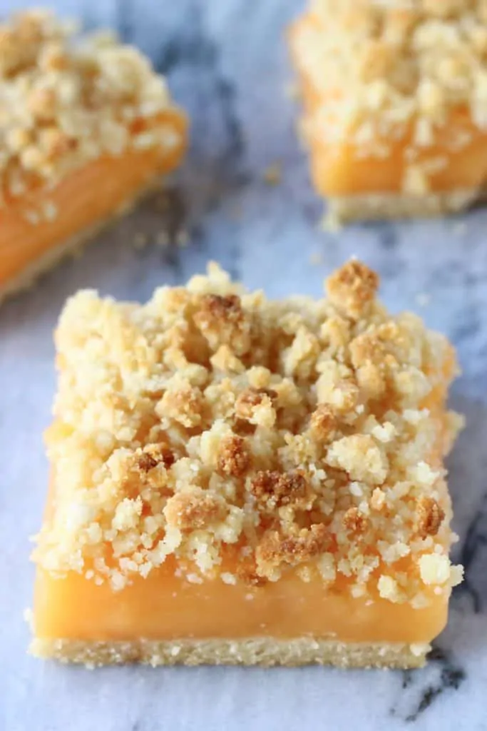 Three lemon crumble bars on a marble background