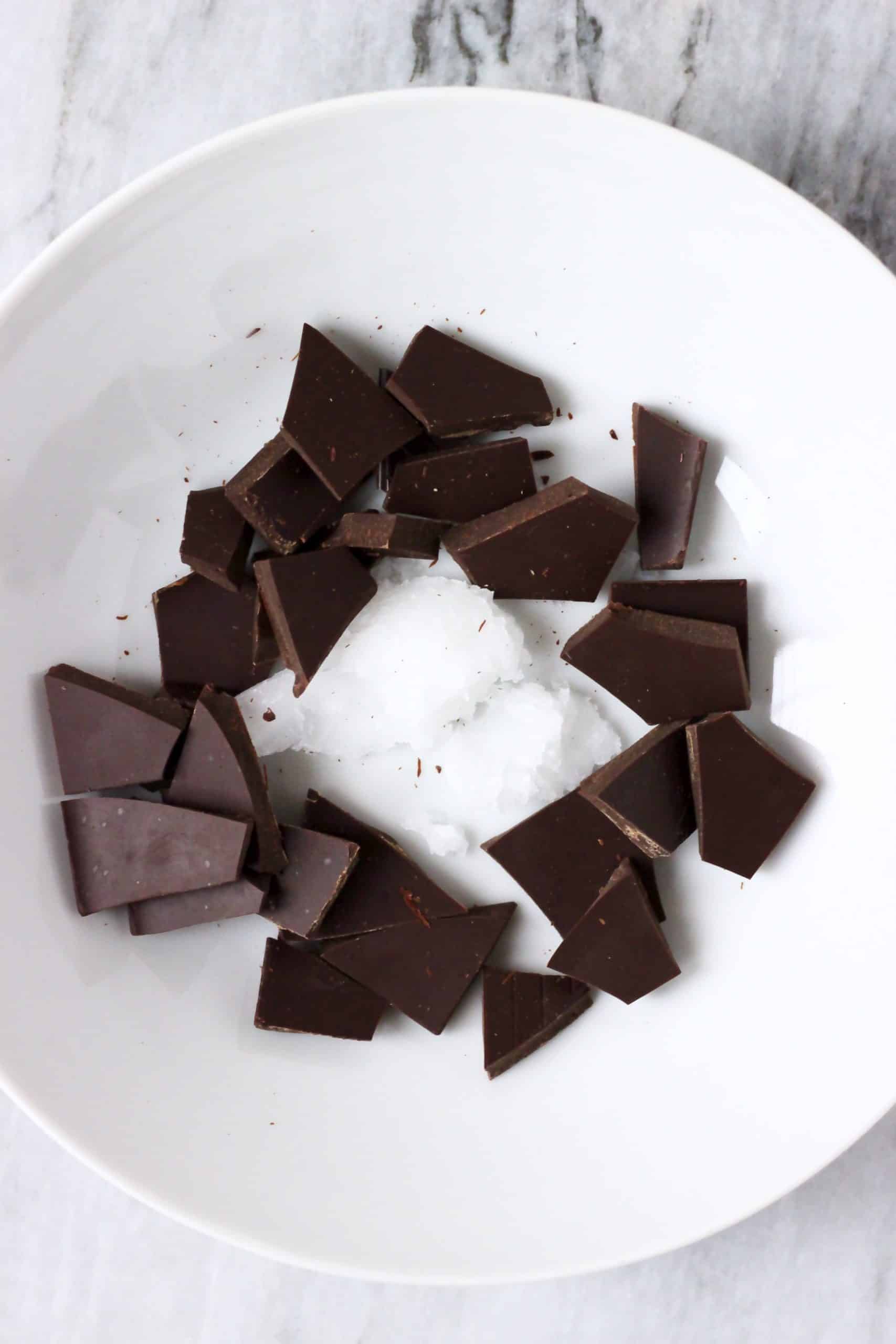 Dark chocolate squares and coconut oil in a white bowl