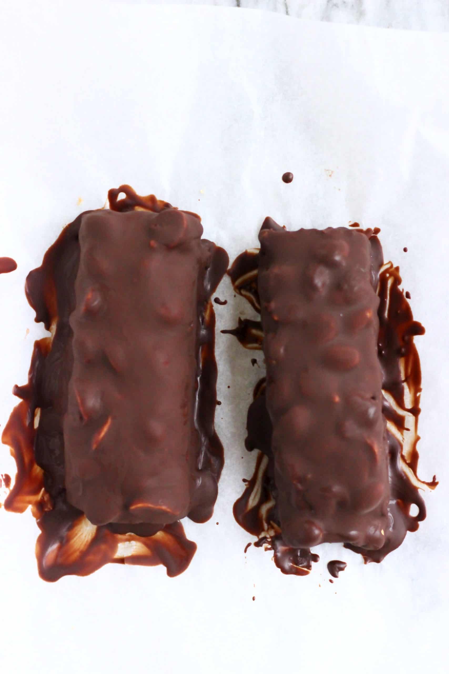 Two vegan snickers bars on a sheet of white baking paper