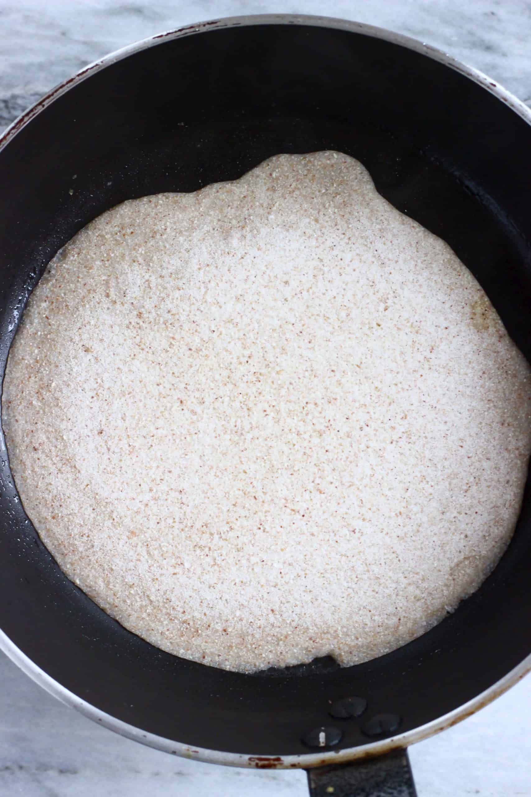 A buckwheat crepe being cooked in a black frying pan