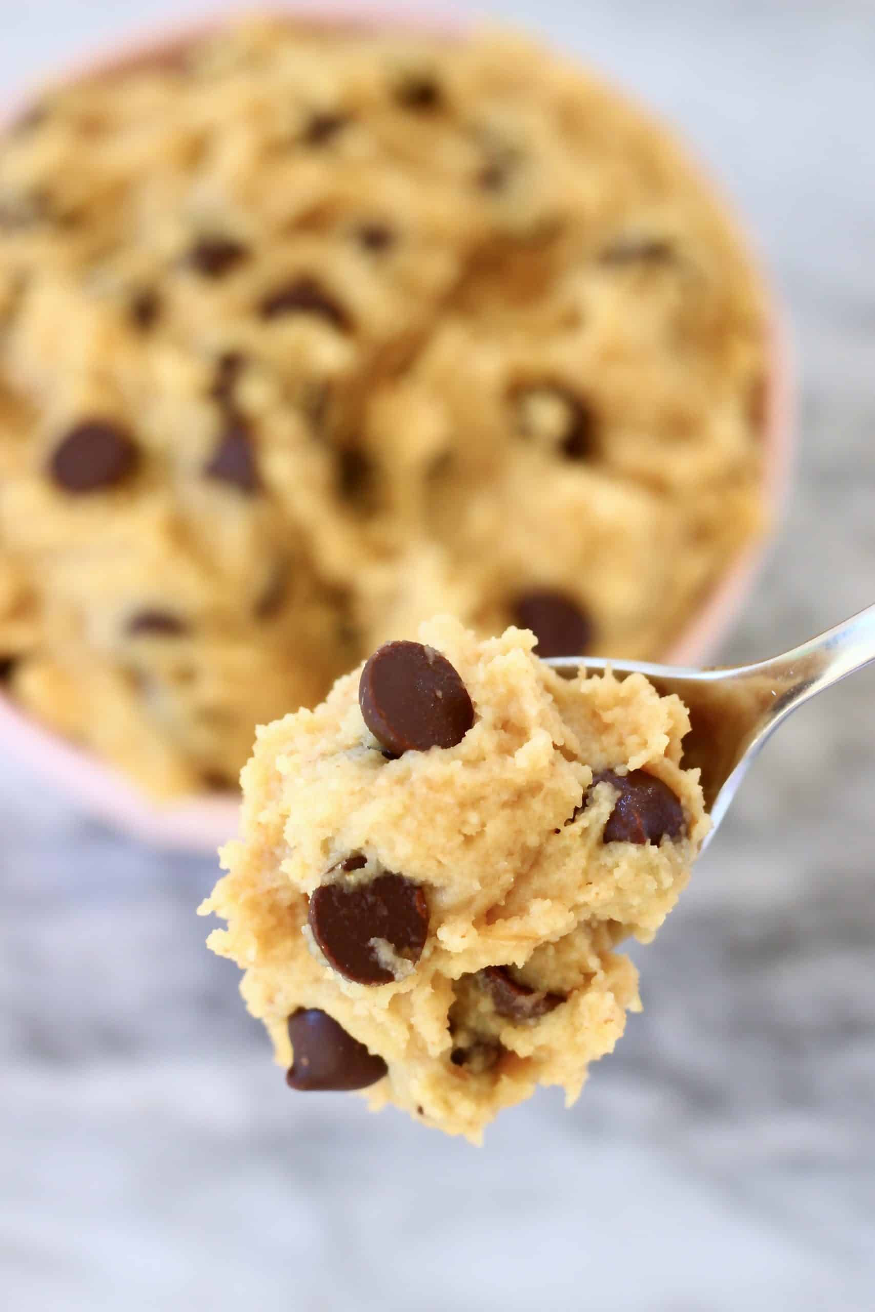 A bowl of no-bake cookie dough with chocolate chips with a spoon lifting up a mouthful