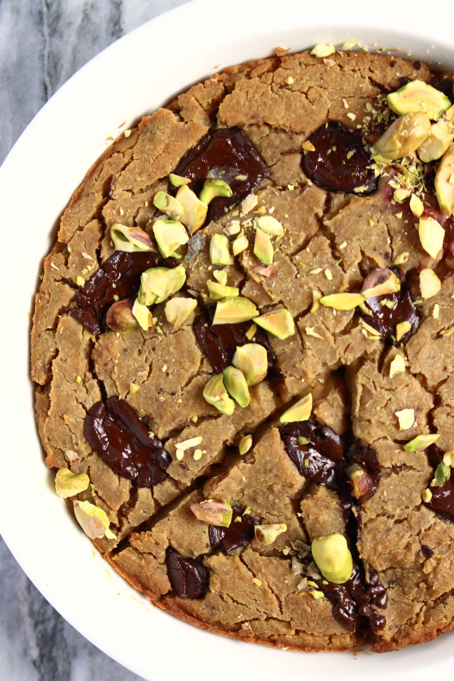Chickpea deep-dish cookie with chocolate chunks in a circular white baking dish