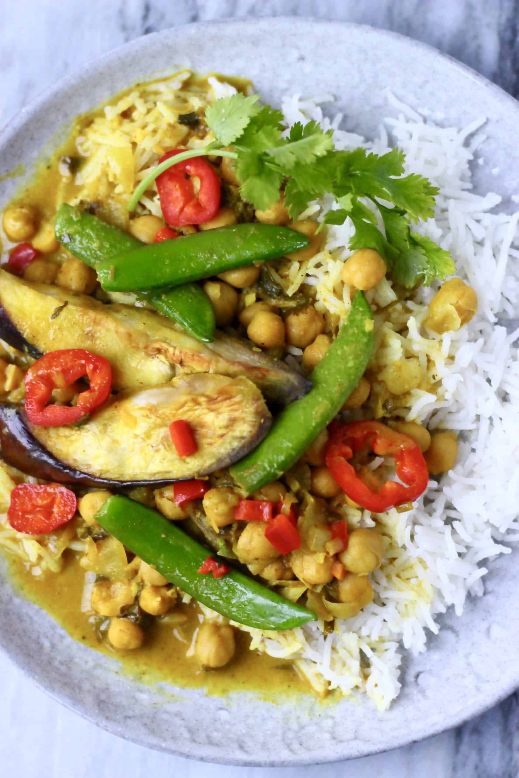 Eggplant chickpea peanut curry with rice on a white plate