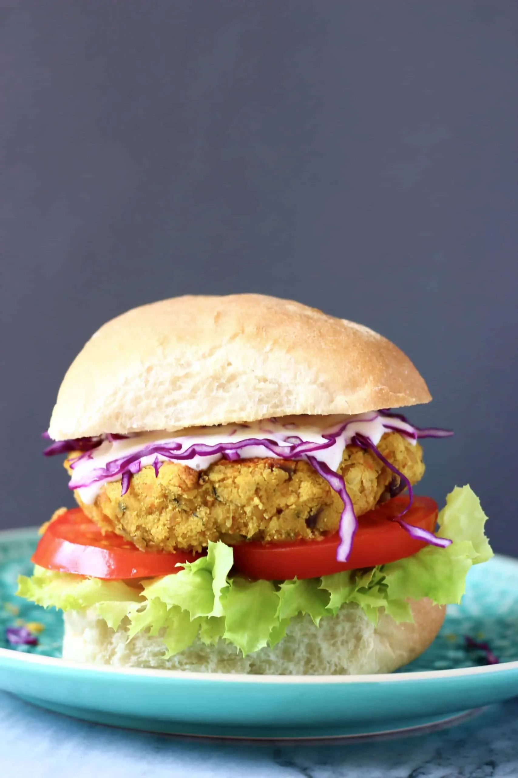 Curried chickpea burger with salad on a blue plate