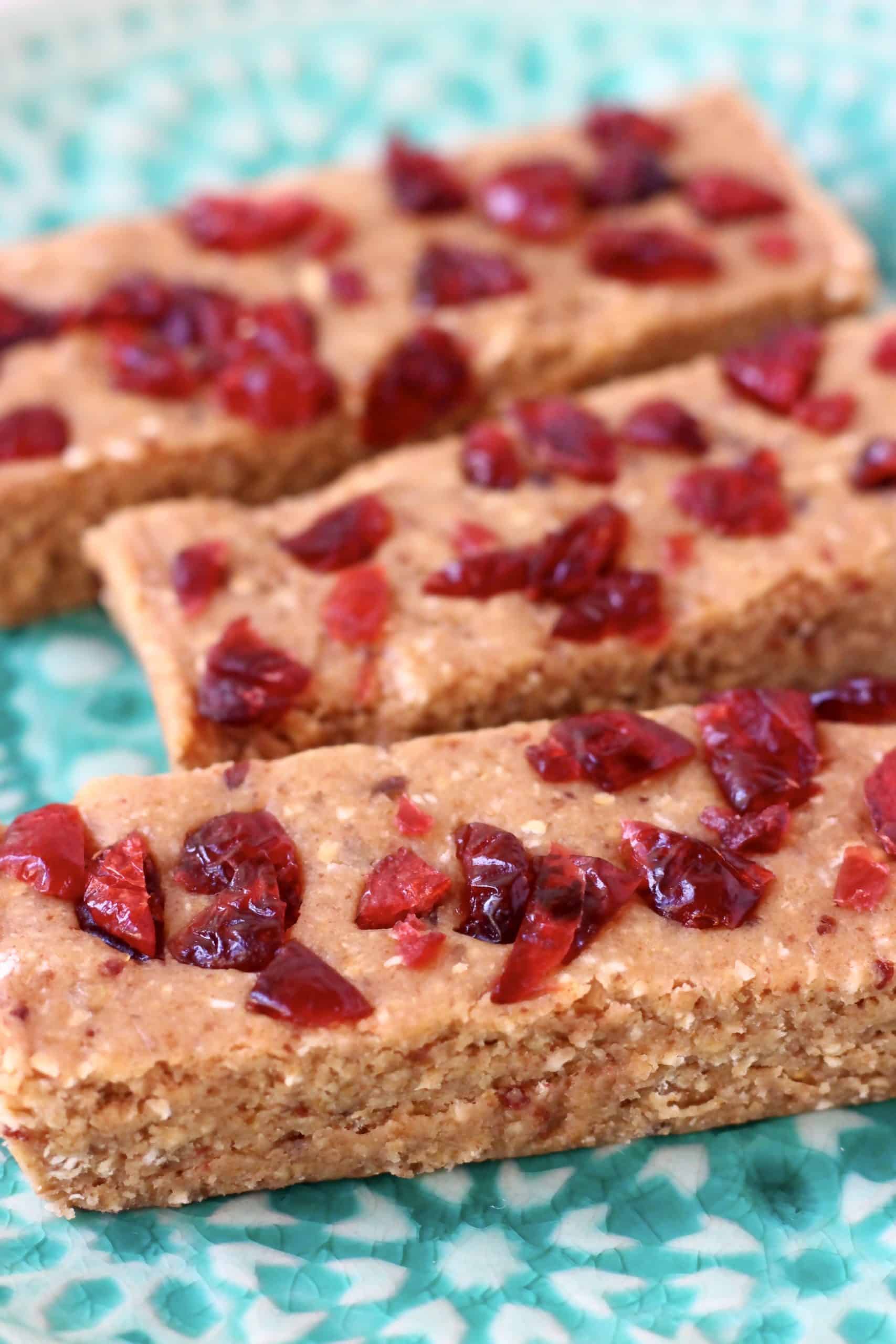 Three protein bars topped with dried cranberries on a blue plate