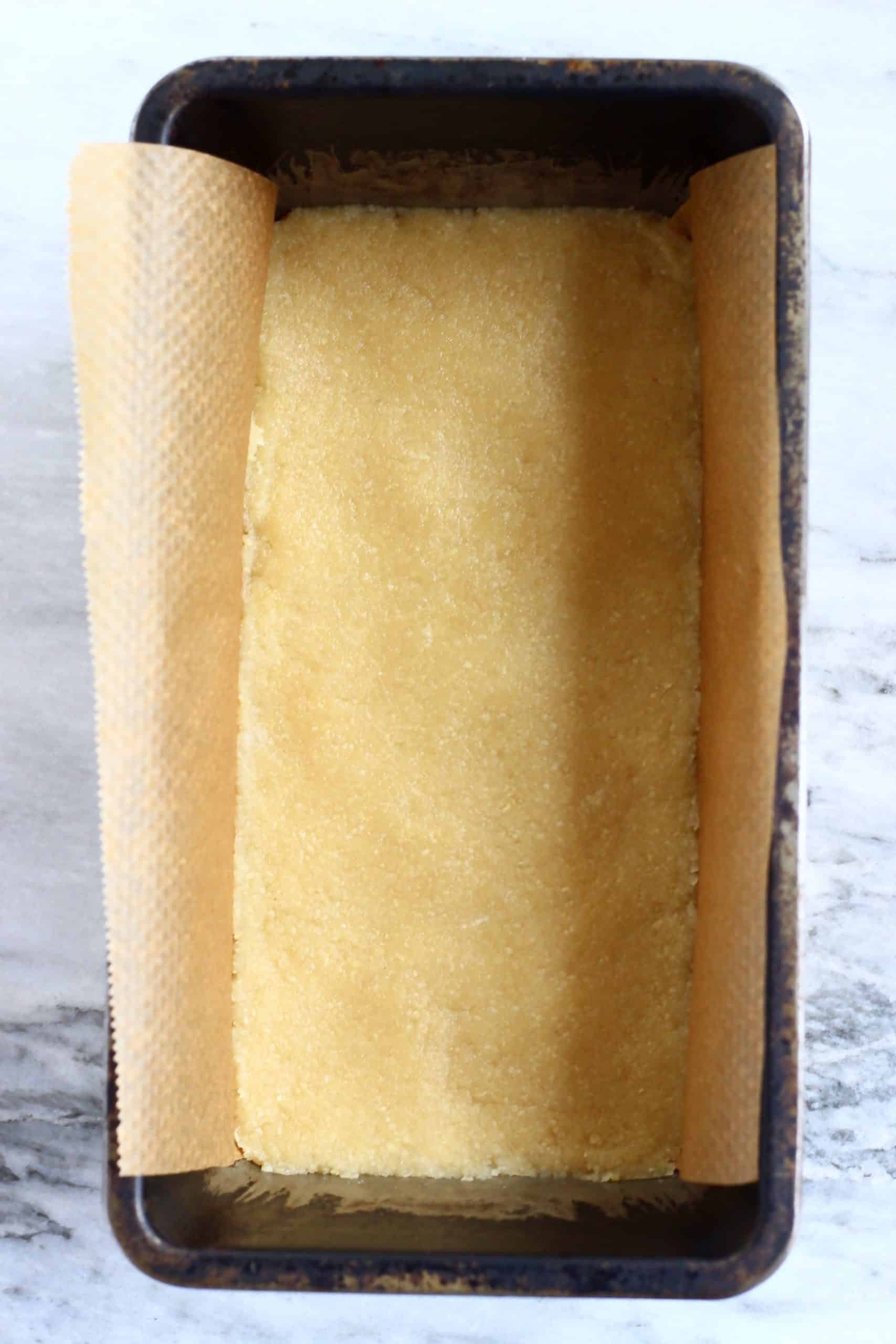 Shortbread cookie dough in a loaf tin lined with baking paper
