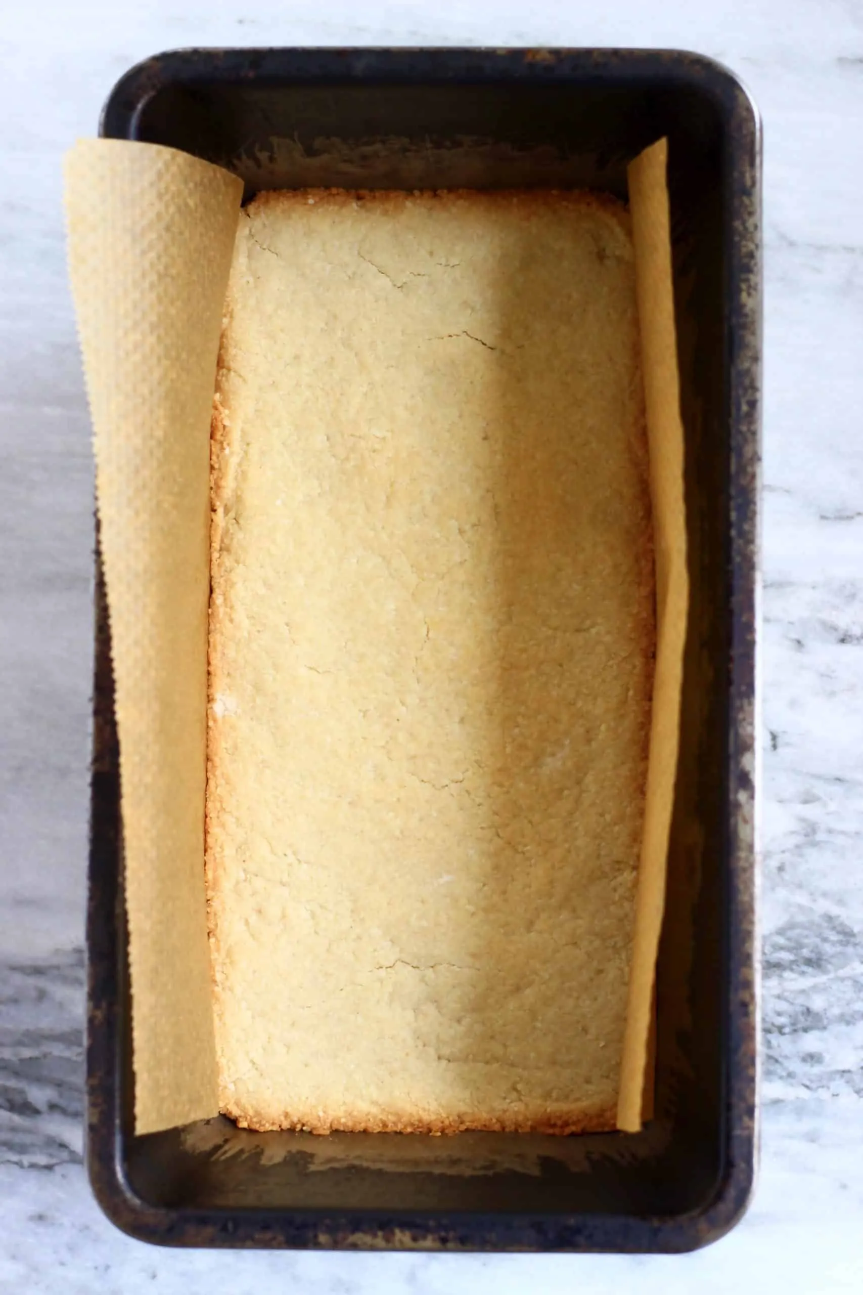 Baked shortbread cookie base in a loaf tin lined with baking paper