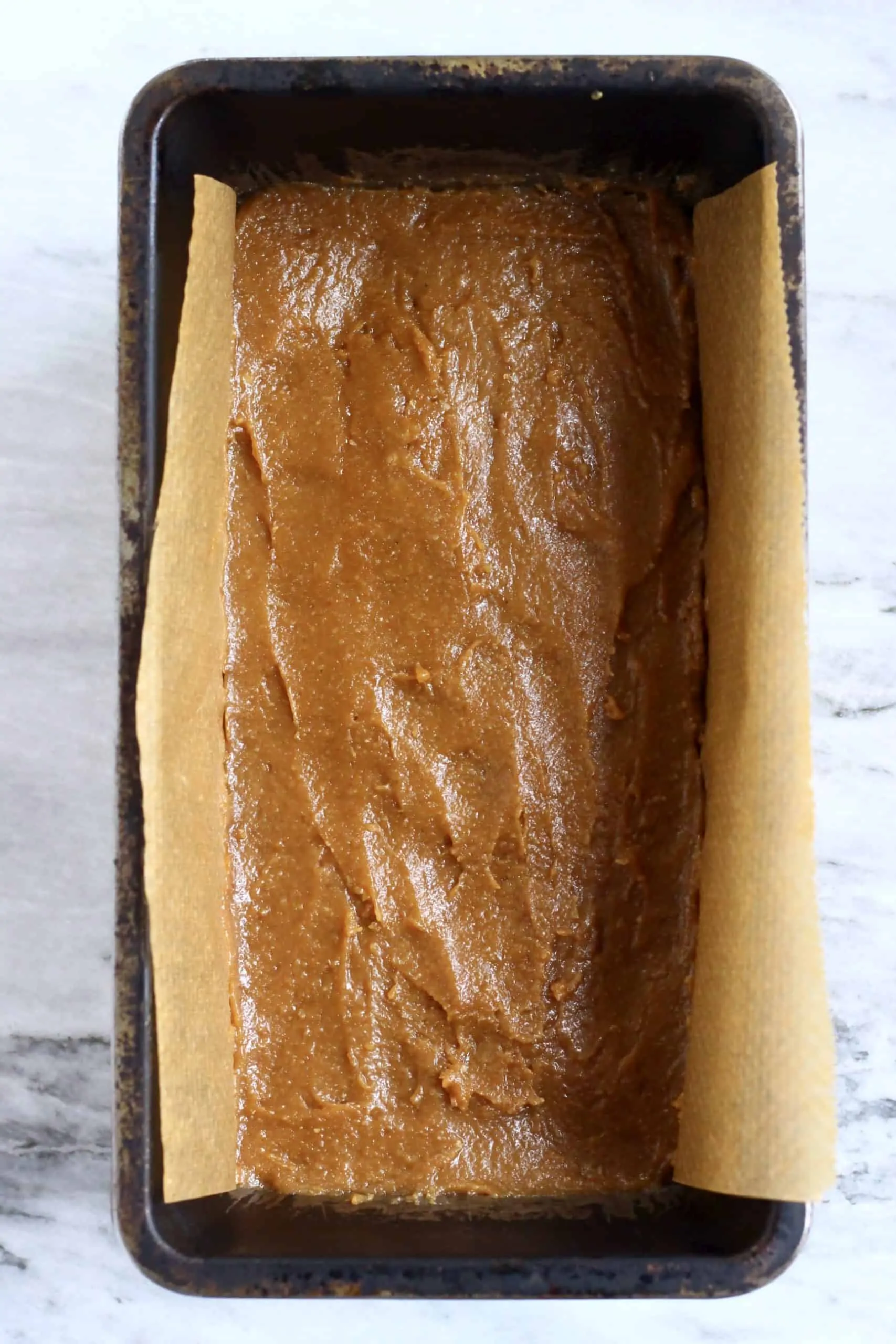 Vegan caramel spread over a shortbread base in a loaf tin lined with baking paper