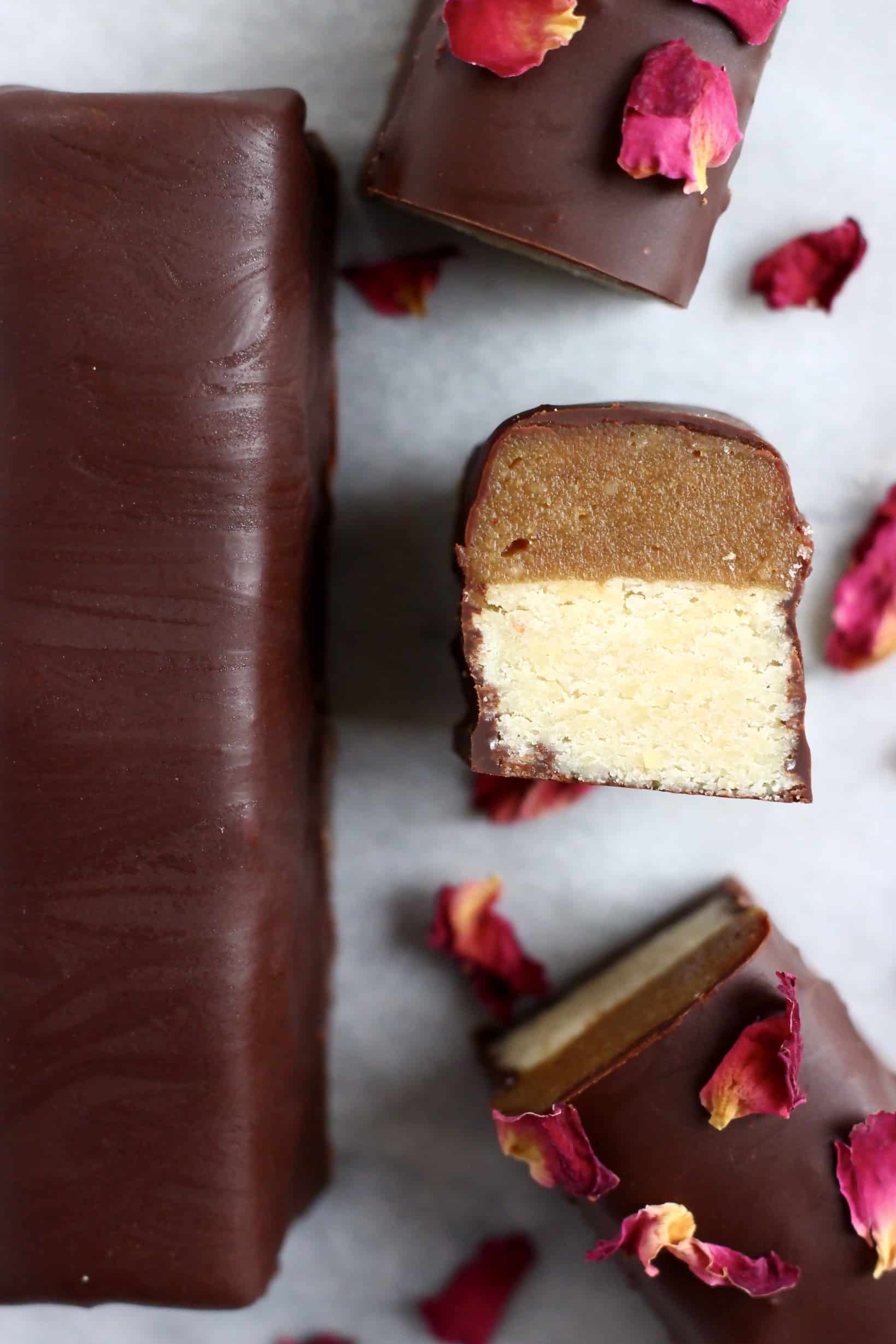 A vegan twix bar cut into three pieces with a whole bar next to it on a piece of white paper