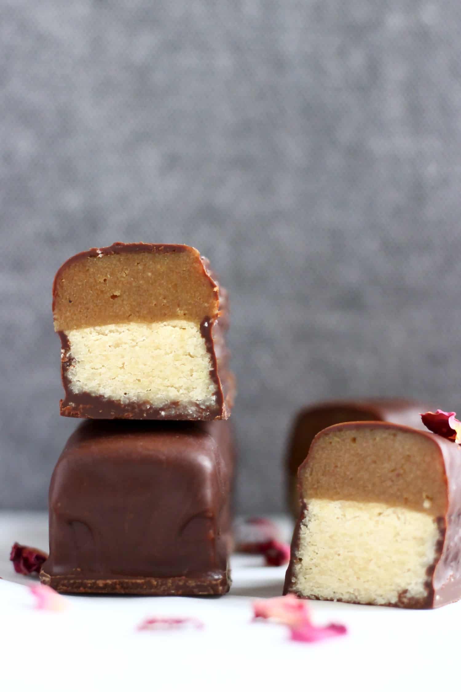 A vegan twix bar cut in half on top of a whole bar against a grey background