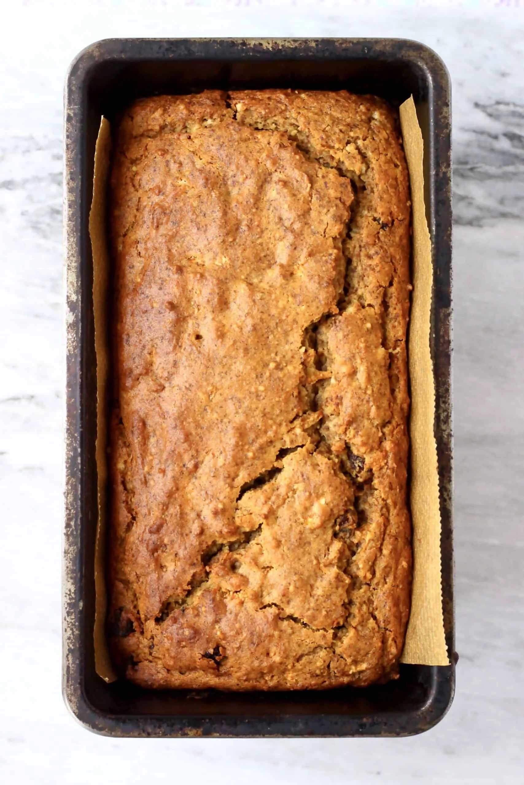 A loaf of vegan carrot bread in a loaf tin lined with baking paper