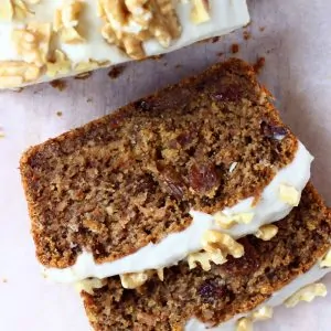 Two slices of vegan carrot bread topped with frosting and walnuts
