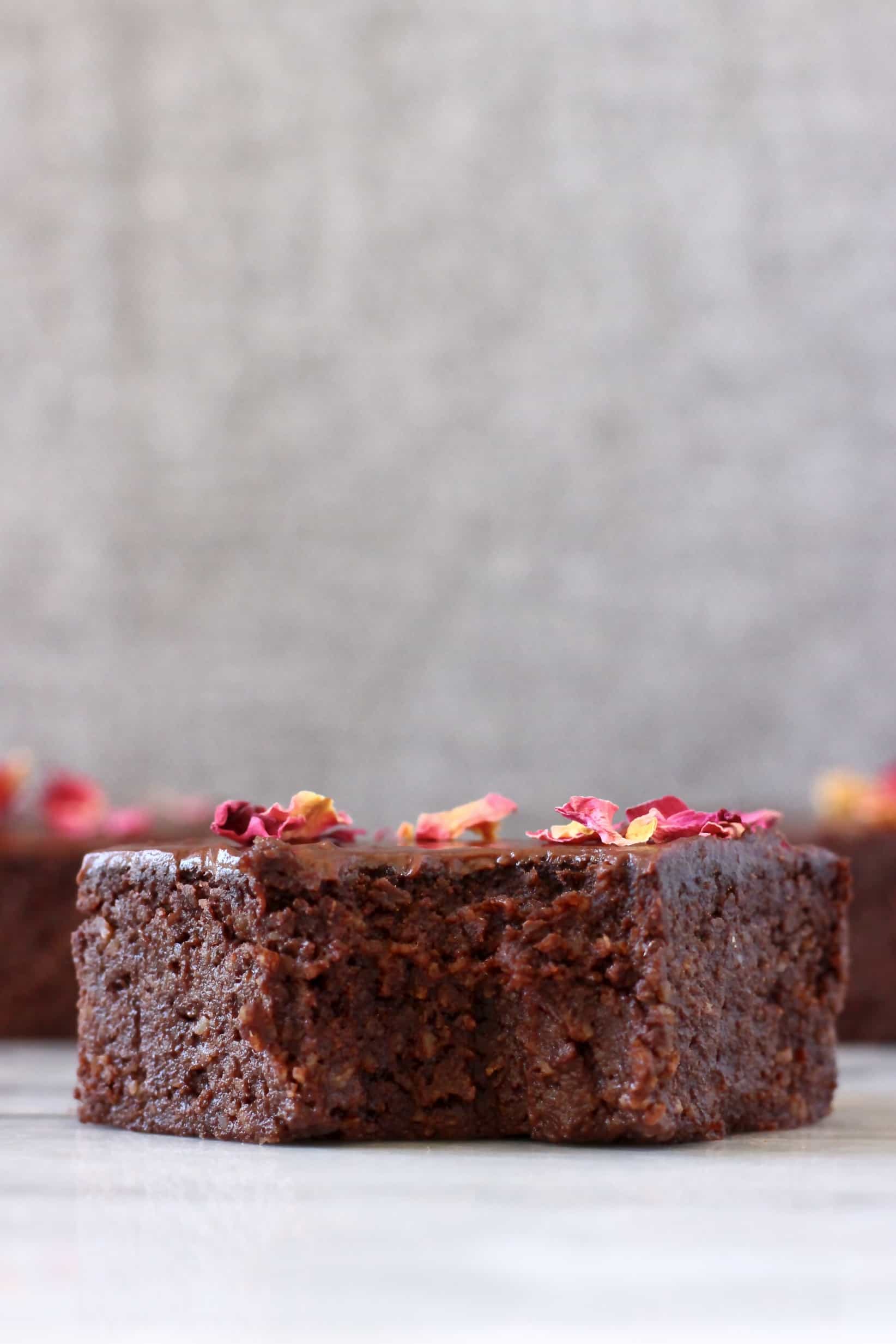 Three avocado brownies with chocolate frosting and rose petals with a bite taken out of one