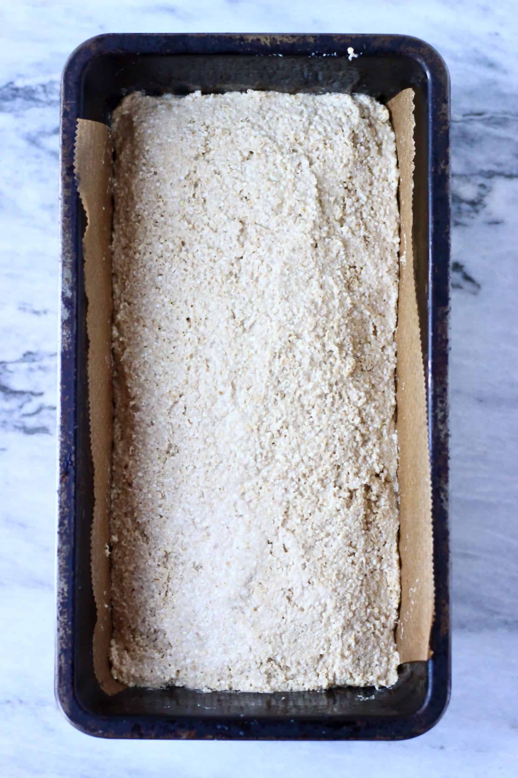 Quinoa bread batter in a loaf tin lined with baking paper