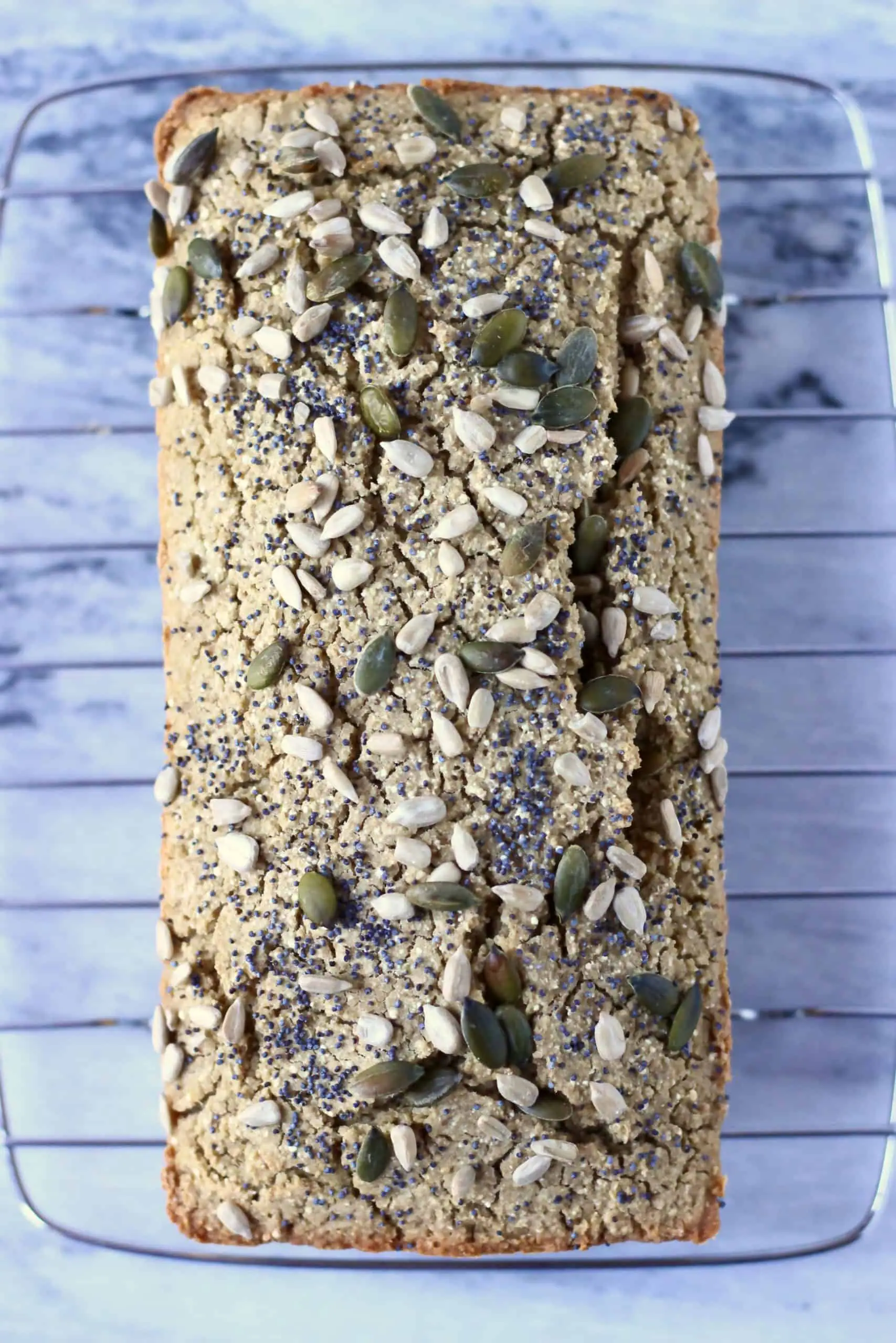 Quinoa bread topped with mixed seeds on a wire rack