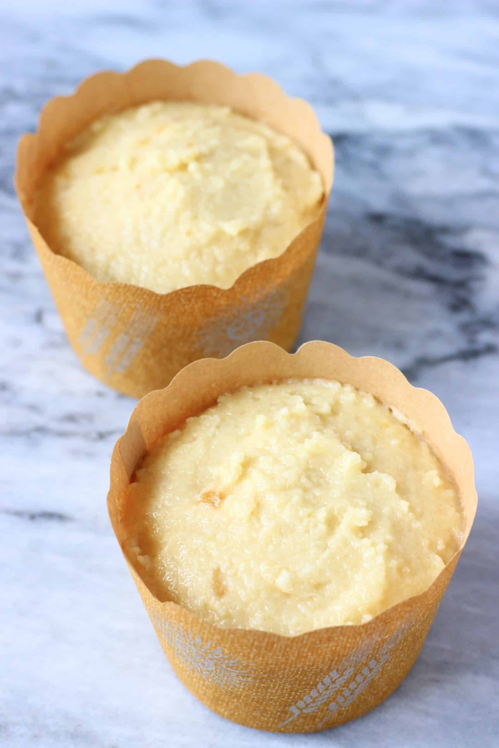 Raw gluten-free vegan orange muffin batter in two brown muffin cases