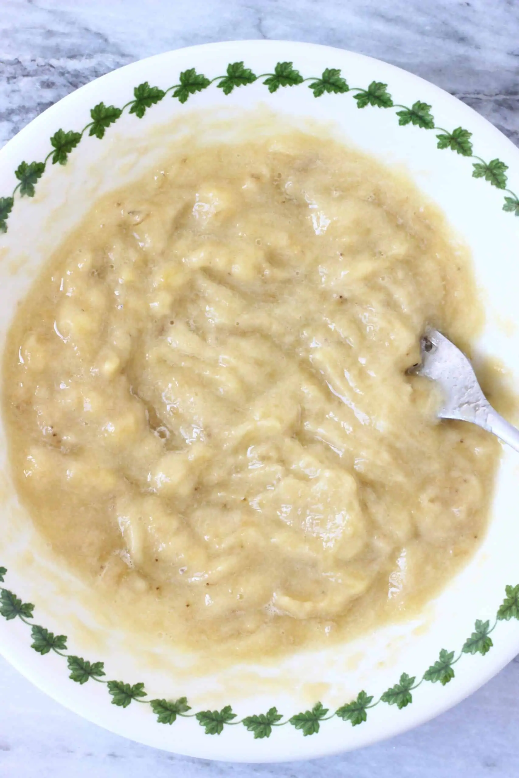 Mashed bananas in a bowl with a fork