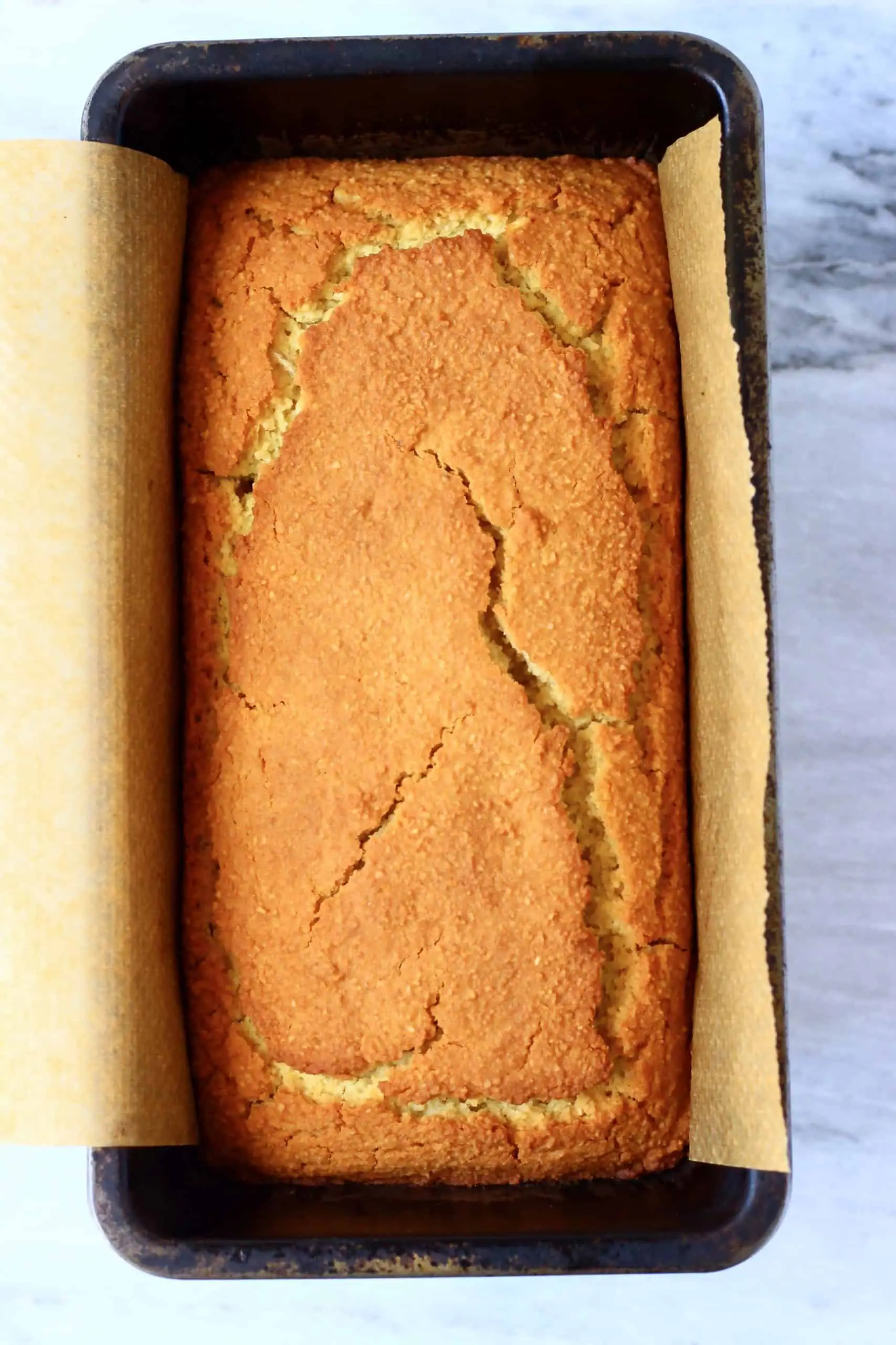 A loaf of gluten-free vegan orange drizzle cake in a loaf tin