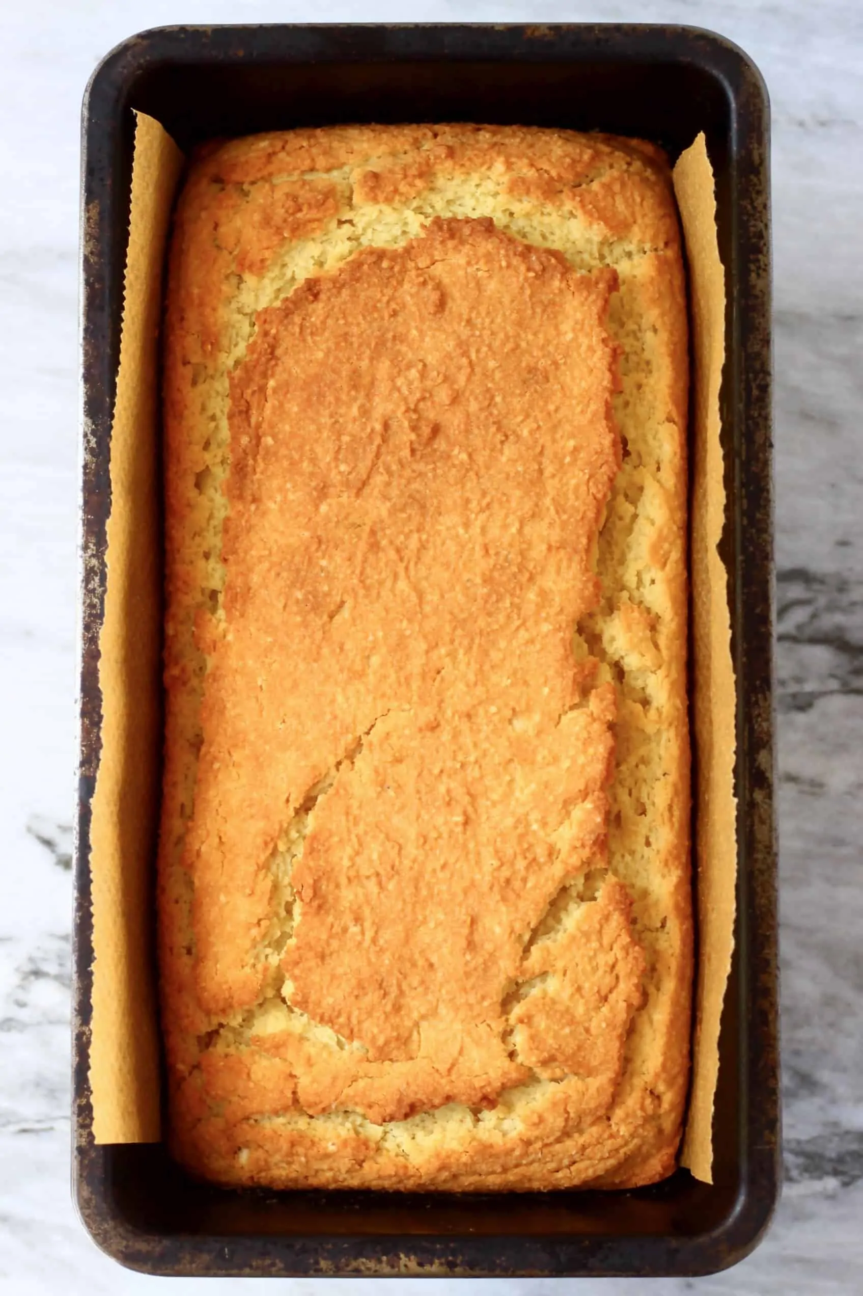 A loaf of gluten-free vegan orange pound cake in a loaf tin