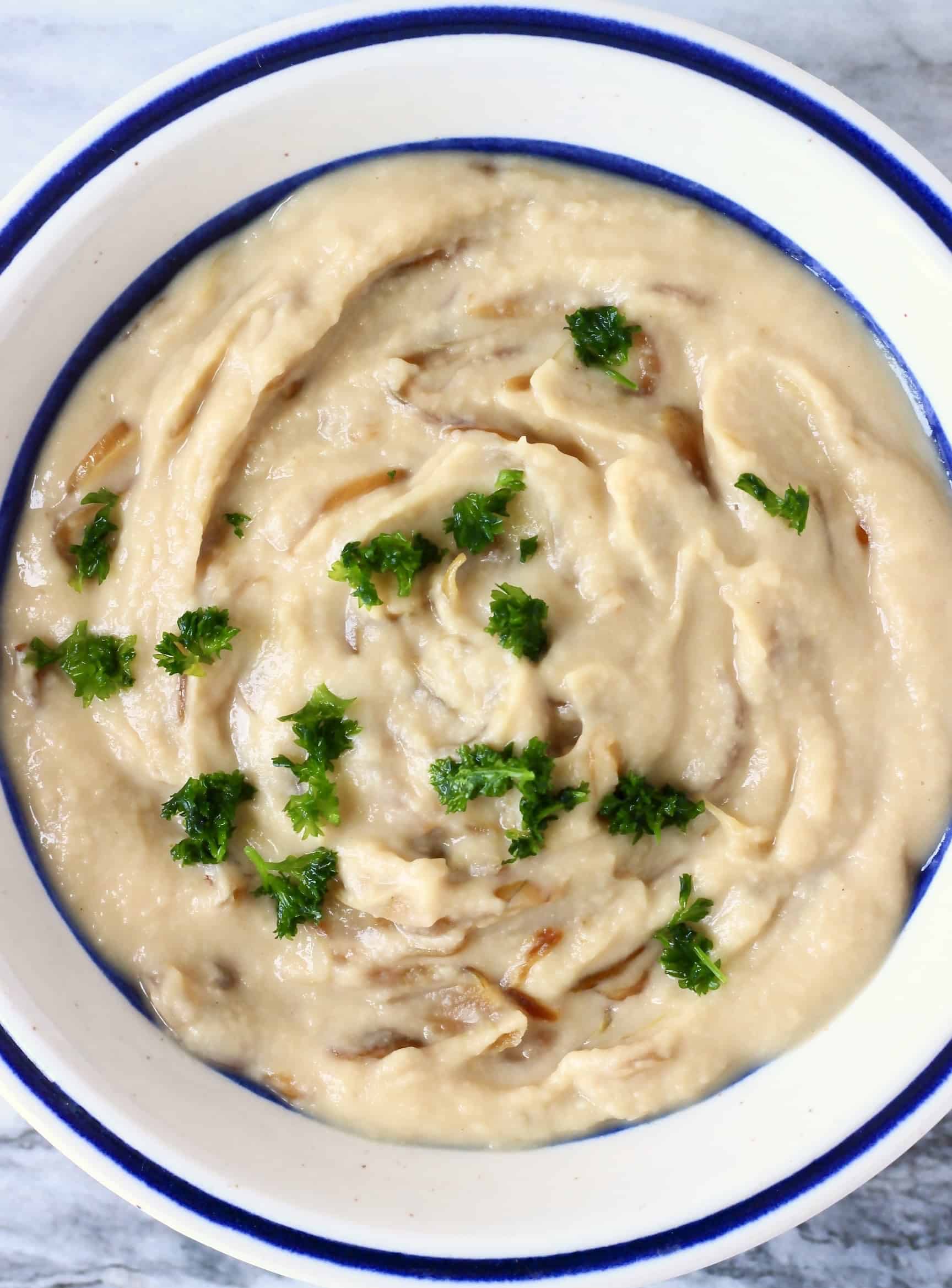 Vegan French onion dip topped with parsley in a white bowl
