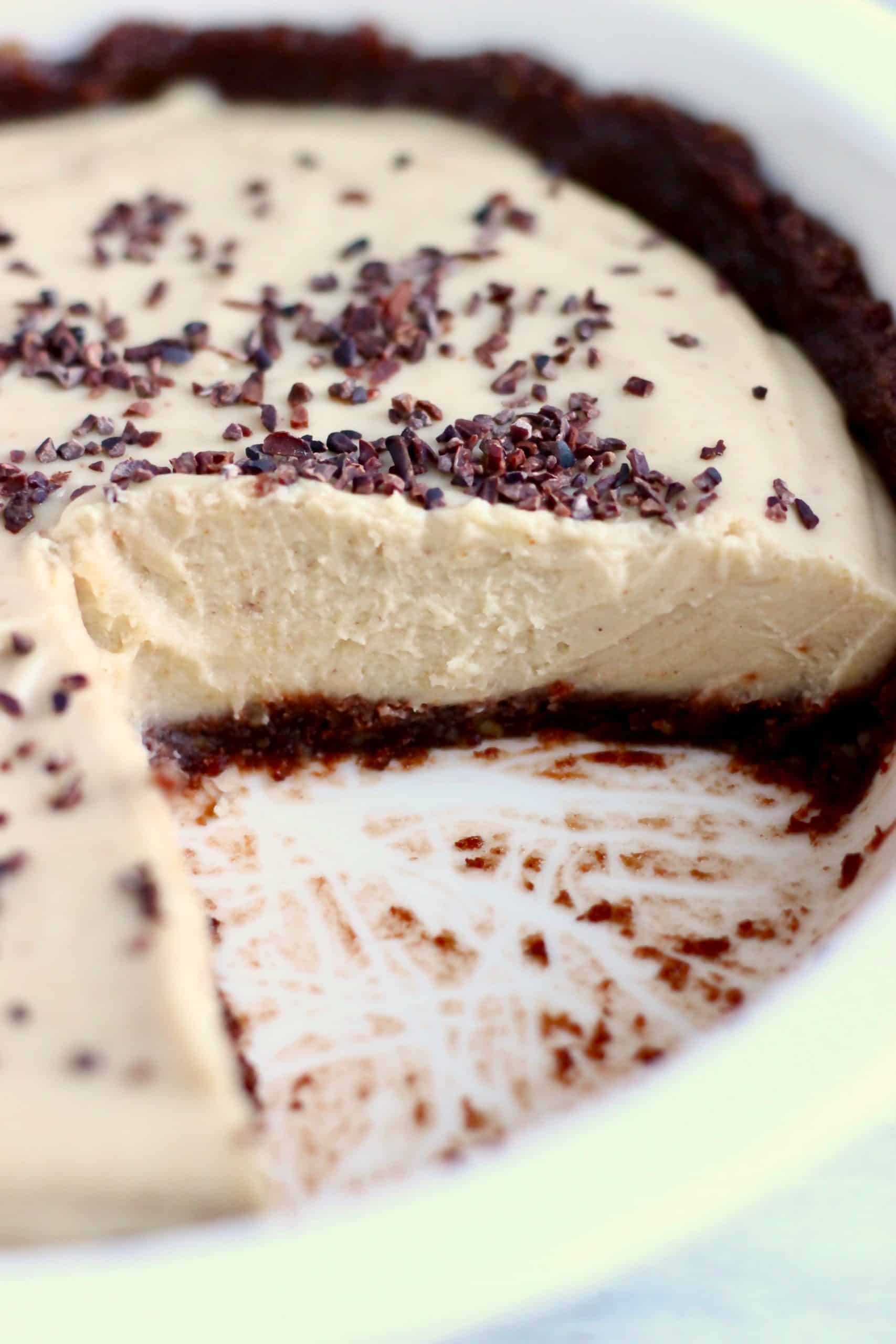 Pastel de mantequilla de maní vegano con corteza de chocolate y relleno de mantequilla de maní en un molde para pastel blanco