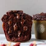 Two gluten-free vegan chocolate zucchini muffins, one cut in half with melted chocolate chips inside