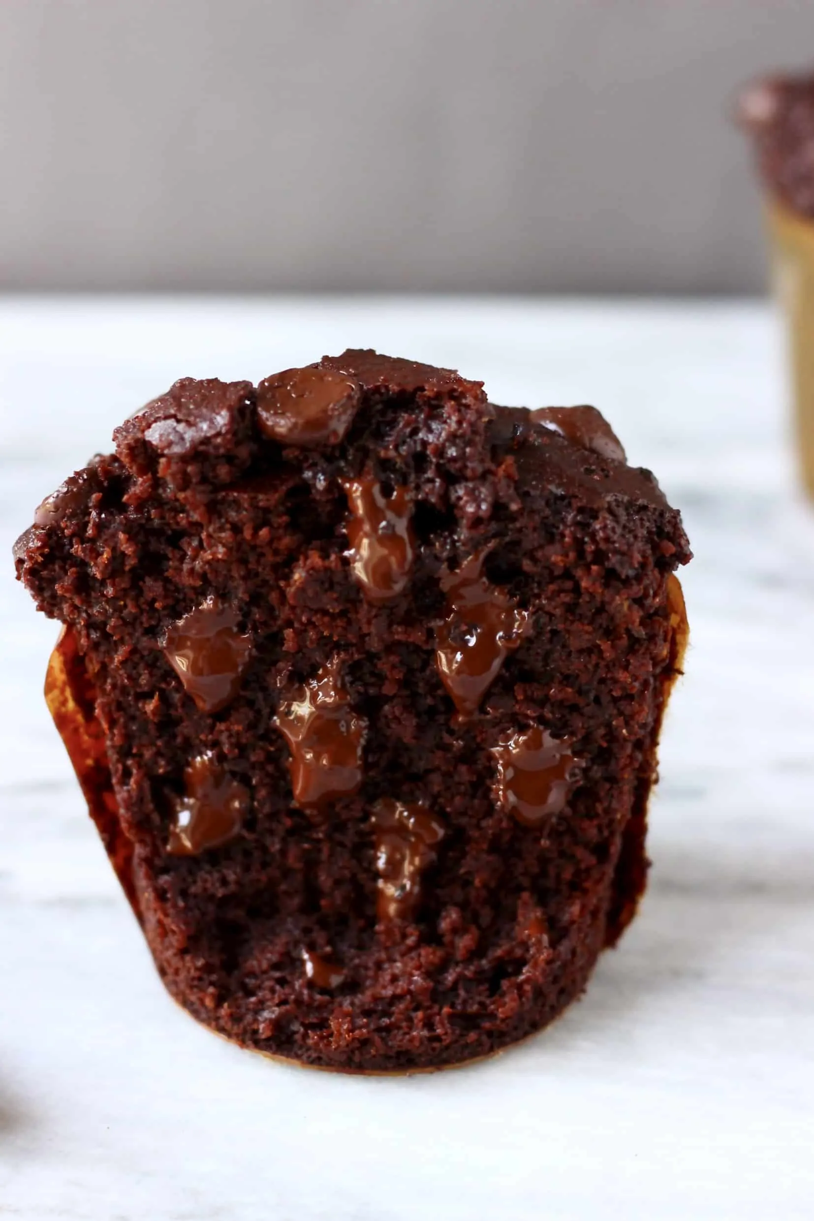 A gluten-free vegan chocolate zucchini muffin cut in half with melted chocolate chips inside