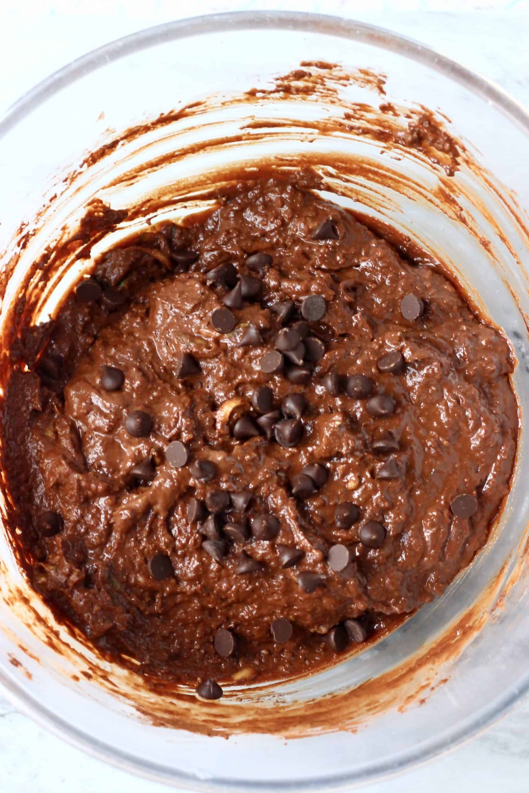 Gluten-free vegan chocolate zucchini muffins batter with chocolate chips in a glass bowl