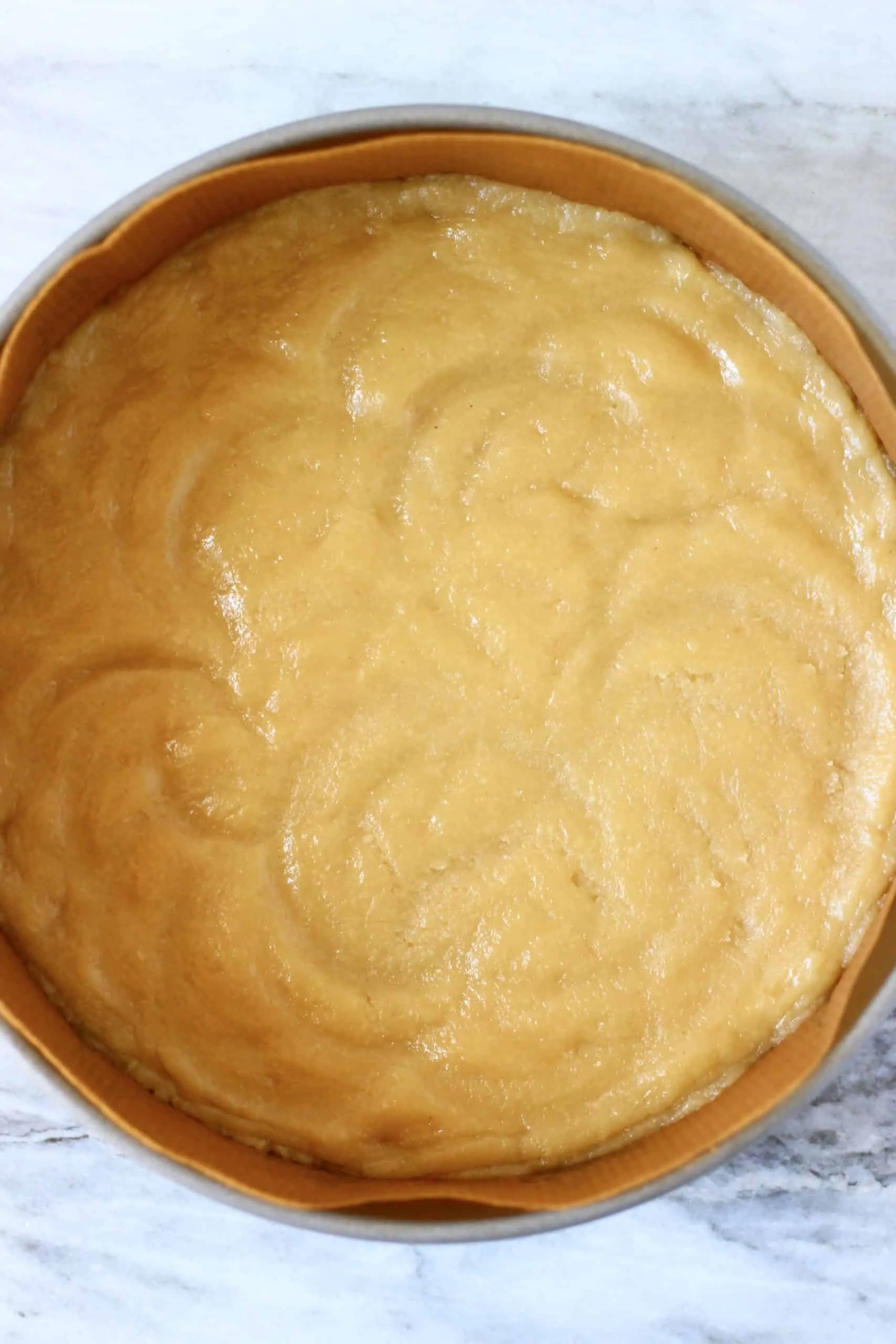 Raw cheesecake crust dough on the bottom of a springform baking tin